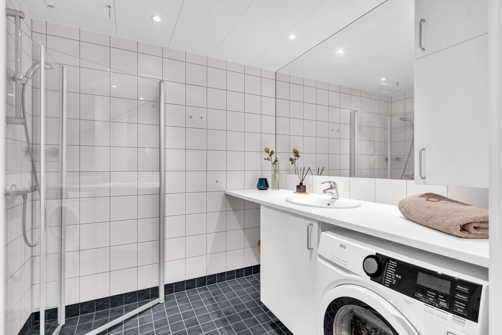 Flislagt bad med varmekabler i gulv og opplegg for vaskemaskin og tørketrommel. Galleribilde