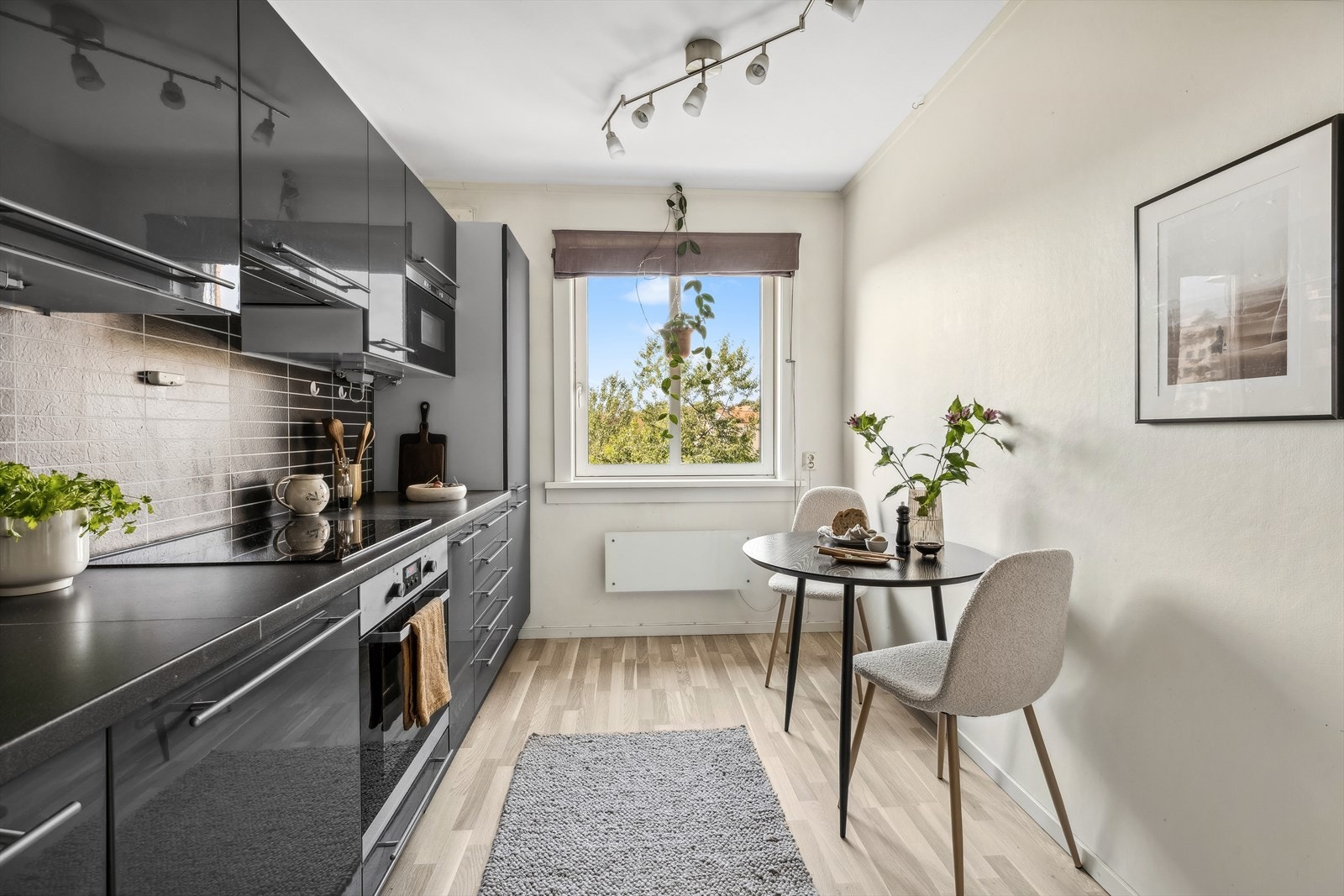 Kjøkkeninnredning fra 2010 med grå høyglansfronter, laminat benkeplate med nedfelt oppvaskkum, 1-greps blandebatteri og fliseimitert respatexplate på vegg over benk Galleribilde