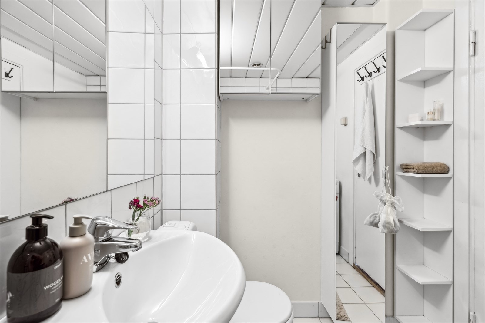 Innredning bestående av servant med underskap, speil, overskap med speildører, wc og dusjhjørne med forheng. Det er plass og opplegg for vaskemaskin. Galleribilde