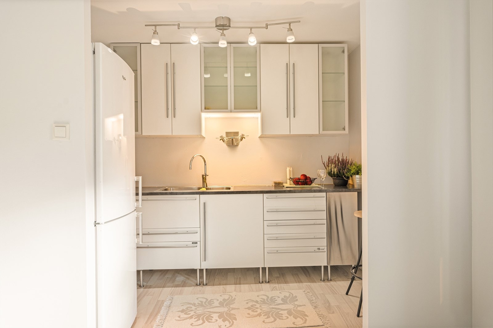 Lys kjøkkeninnredning fra Ikea med slette fronter, to fronter i børstet stål, fire fronter i frostet glass og laminat benkeplate. Galleribilde