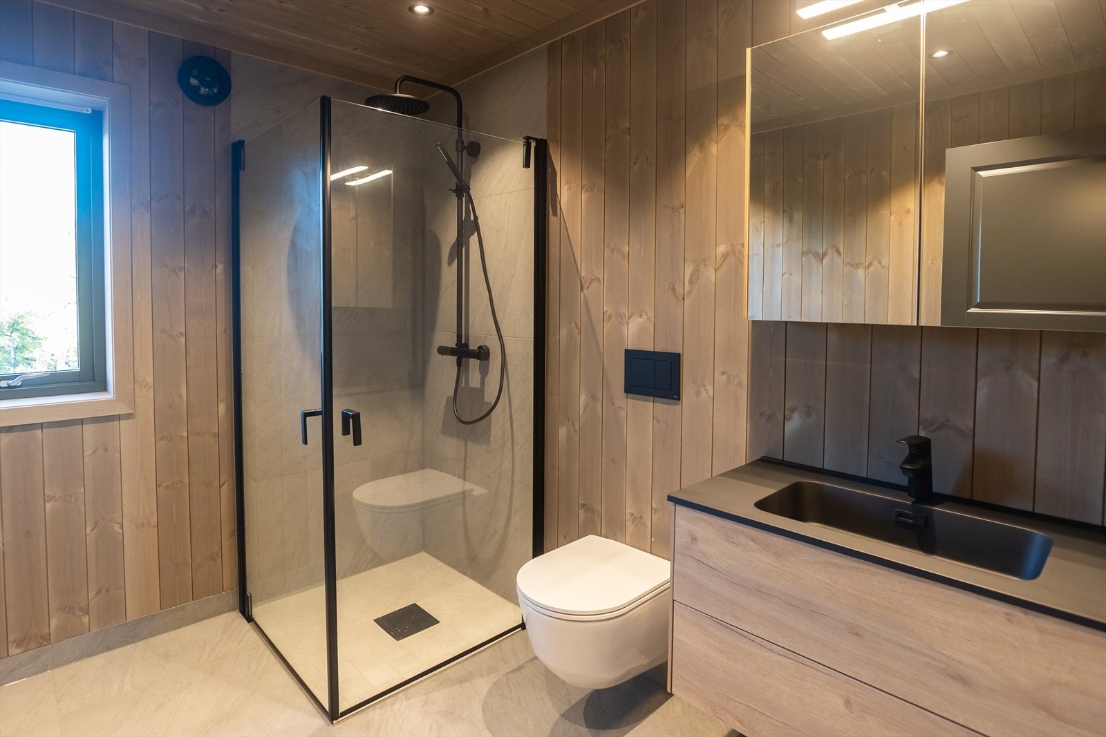 Lekkert hovedbad med dusjhjørne, veggmontert toalett og servantinnredning. Galleribilde