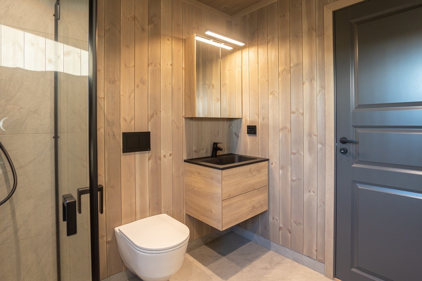 Bad nr 2 er også utstyrt med dusjhjørne, veggmontert toalett og servantinnredning. Galleribilde