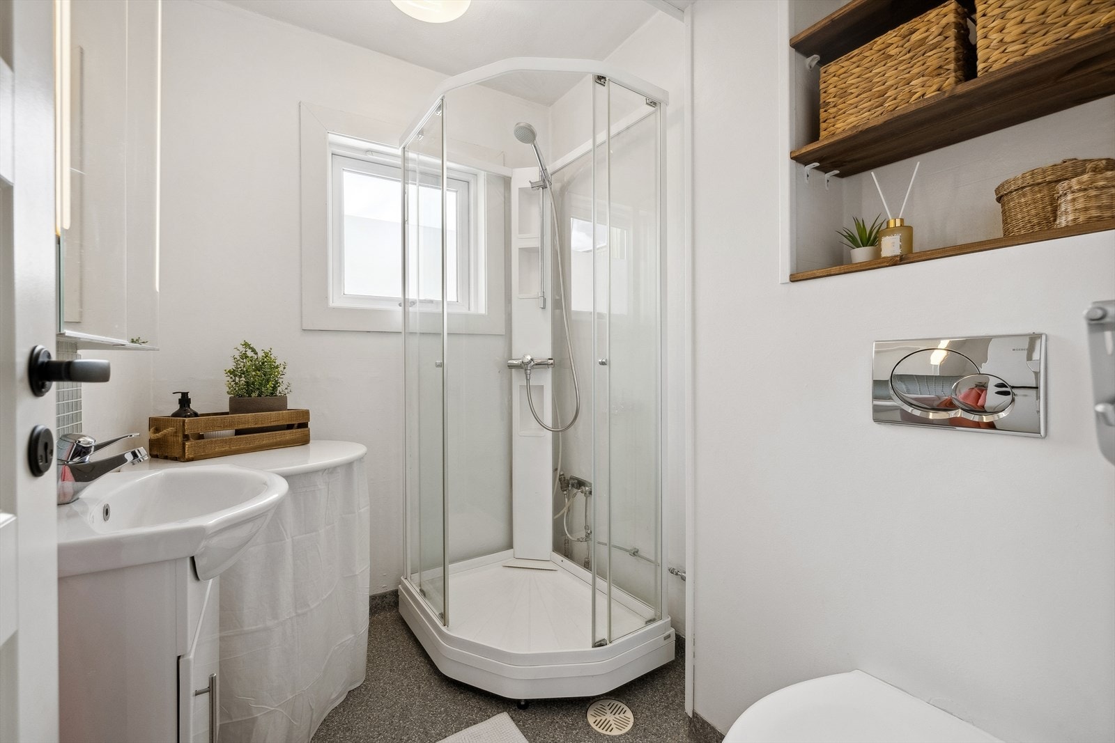 Badet er utført med gulvbelegg og malte veggflater - Rommet er utstyrt med dusjkabinett fra 2017, veggmontert toalett, opplegg for vaskemaskin og baderomsinnredning Galleribilde