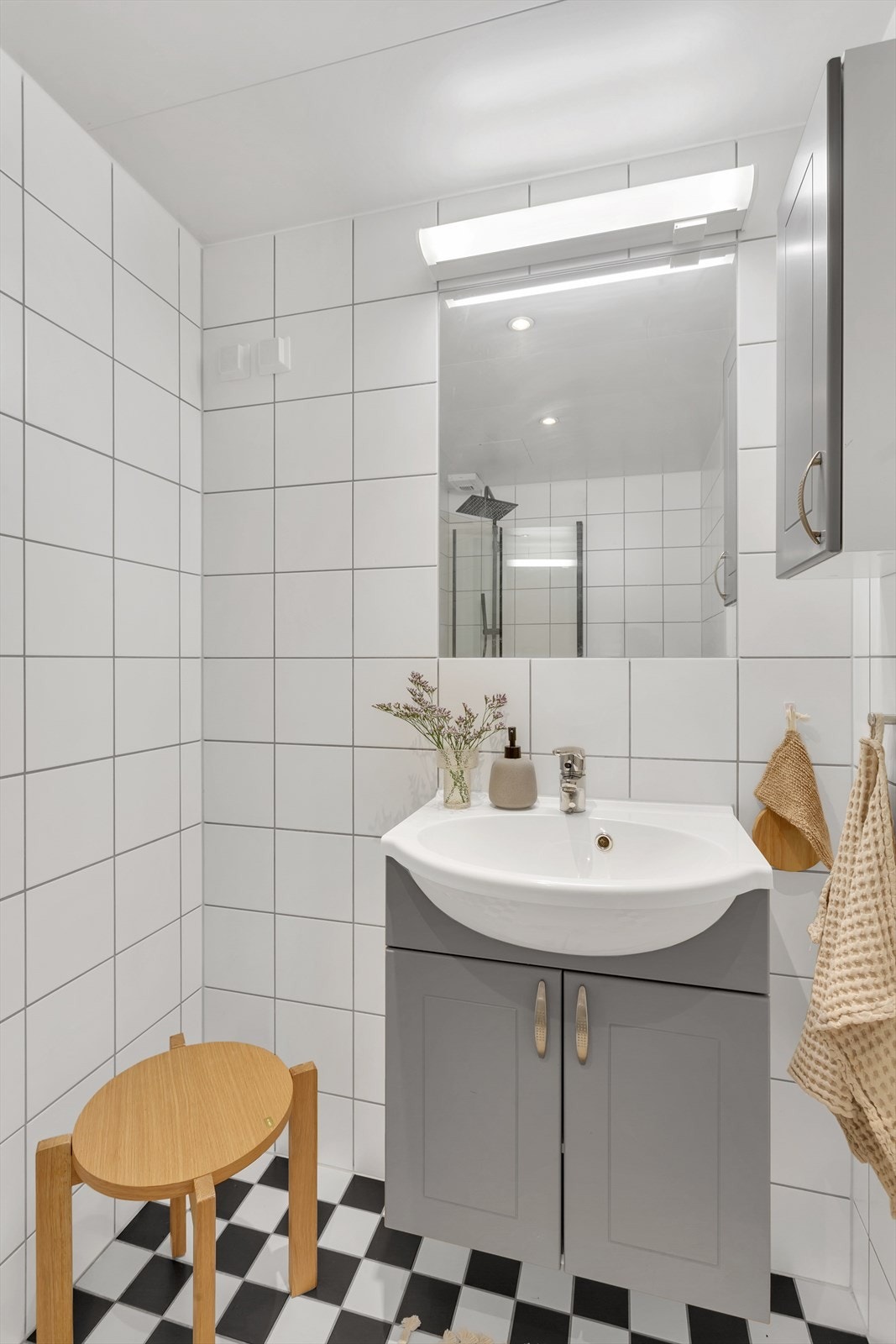 Innredning med heldekkende servanti, vegghengt speil, gulvmontert toalett, dusjhjørne med glassdører og opplegg for vaskemaskin. Galleribilde