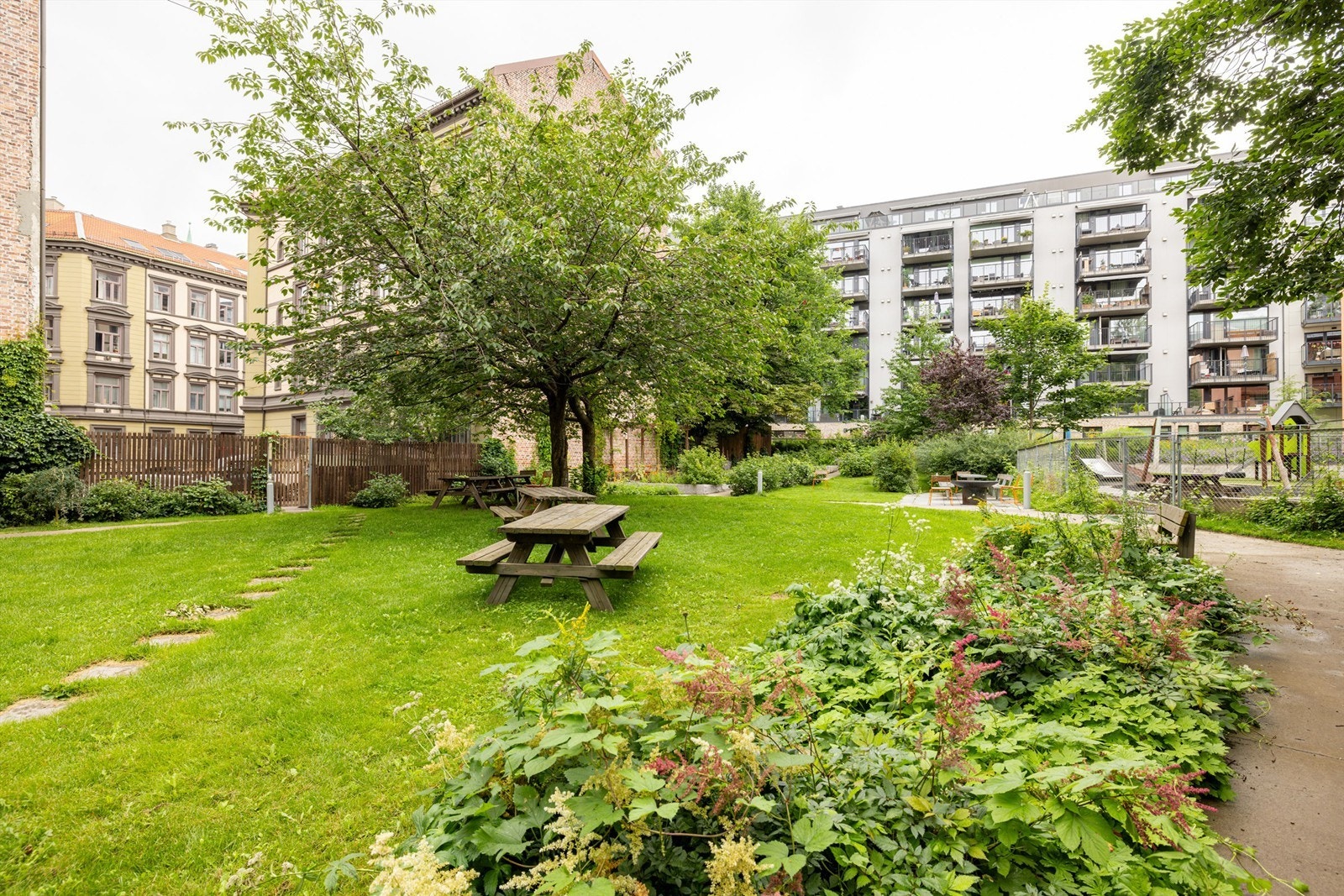 Sameiets fellesareal i bakgården byr på fine grøntområder med beplantning og sittegrupper Galleribilde