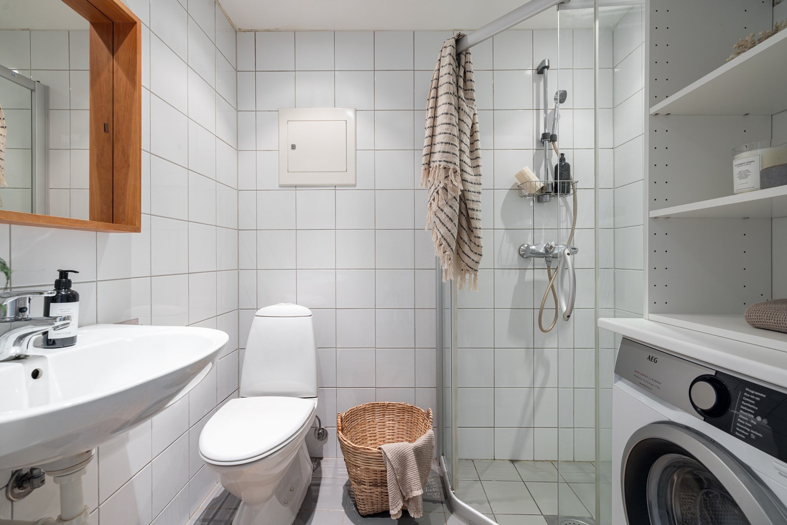 Badet har eget dusjhjørne, egen nisje til vaskemaskin og godt med lagringsplass Galleribilde