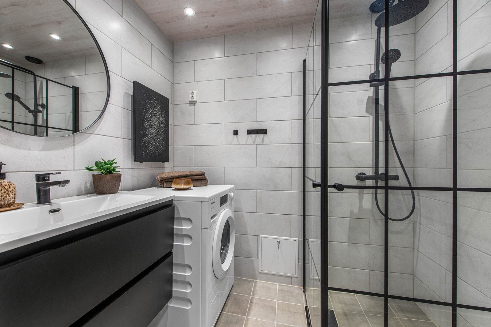 Utstyrt med dusjhjørne med innfellbare dusjdører, opplegg for vaskemaskin, servant i skap og vegghengt toalett. Galleribilde