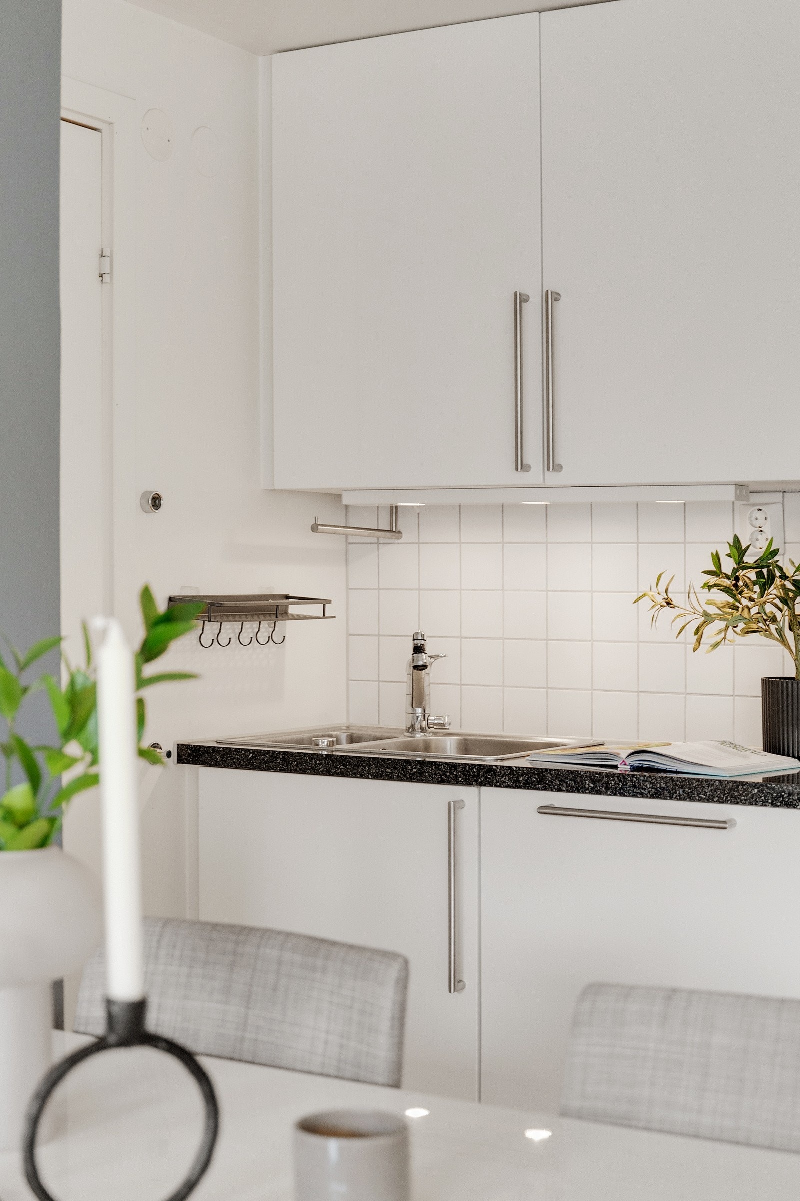 Moderne kjøkkeninnredning med hvite glatte fronter og fliser over benken. Galleribilde