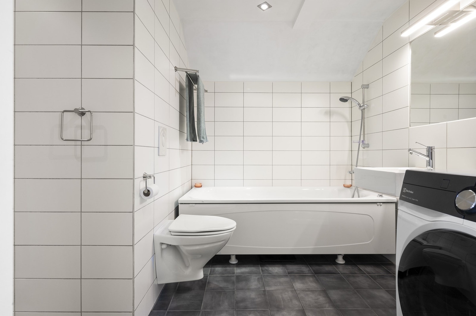 Innredningen består av servant, speil med belysning over servant og vegghengt toalett. Opplegg for vaskemaskin og elektrisk styrt vifte. Galleribilde