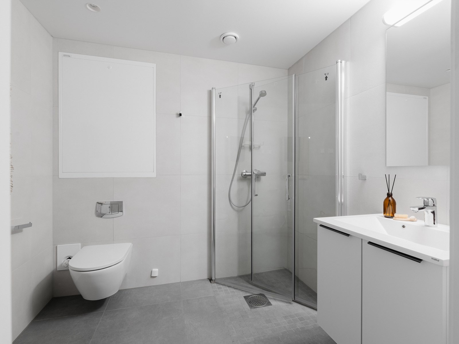 Badet er innredet med vegghengt toalett, dusjhjørne og servant på underliggende servantskap. Galleribilde