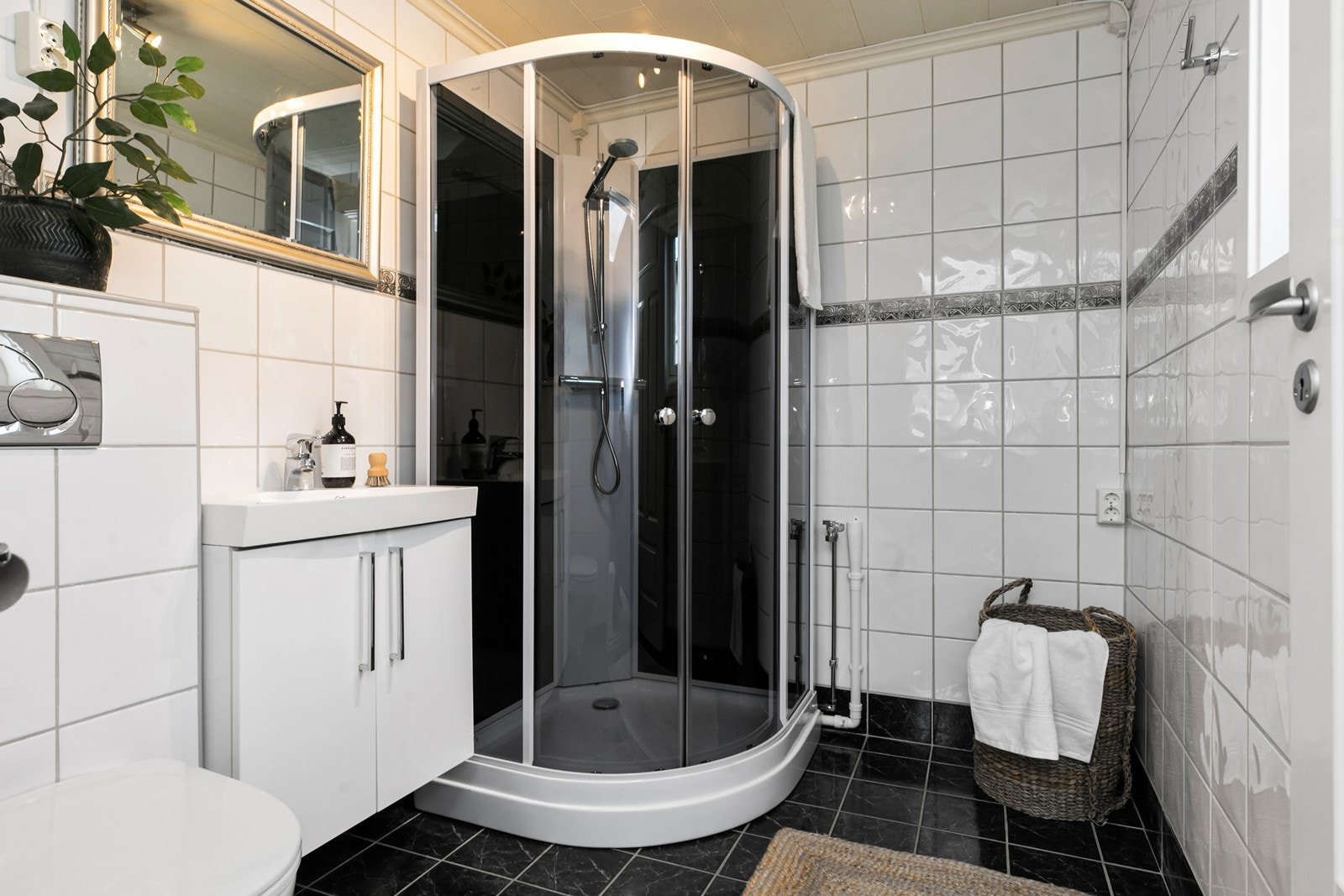 Badet i 1. etasje har dusjkabinett, veggmontert wc, servantinnredning og opplegg for vaskemaskin. Her er det varme i gulvet. Galleribilde