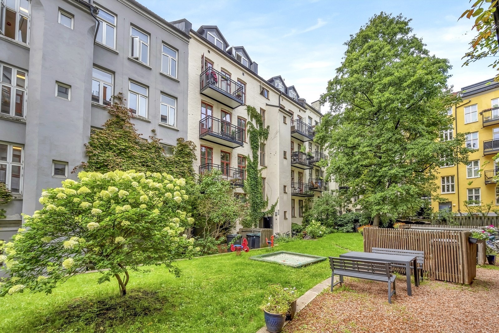 Bakgården er pent opparbeidet med plen, beplantning og hyggelige internveier Galleribilde