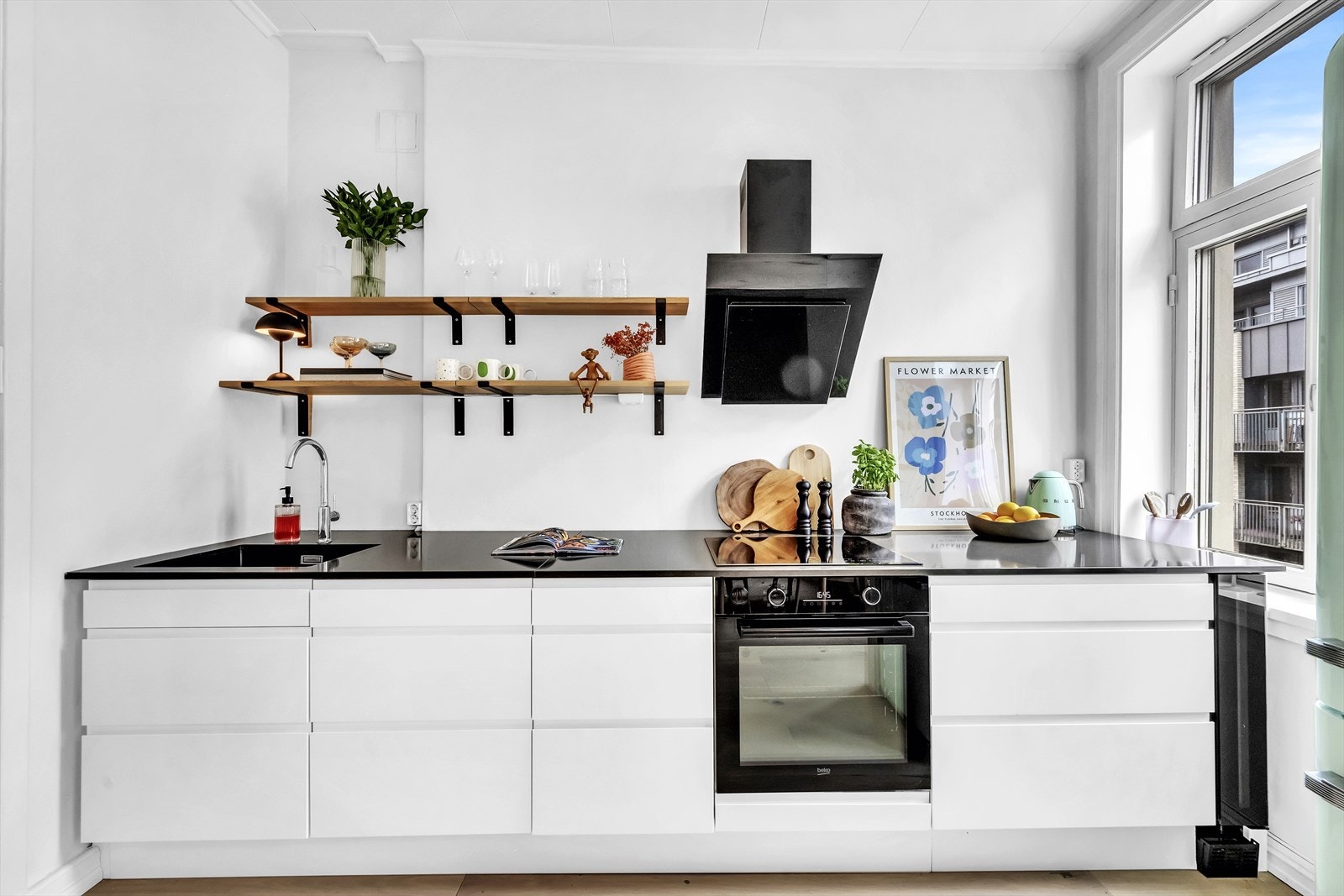 Kjøkkenet har et tidsriktig og åpent uttrykk med kun benkeskap og hyller på vegg Galleribilde