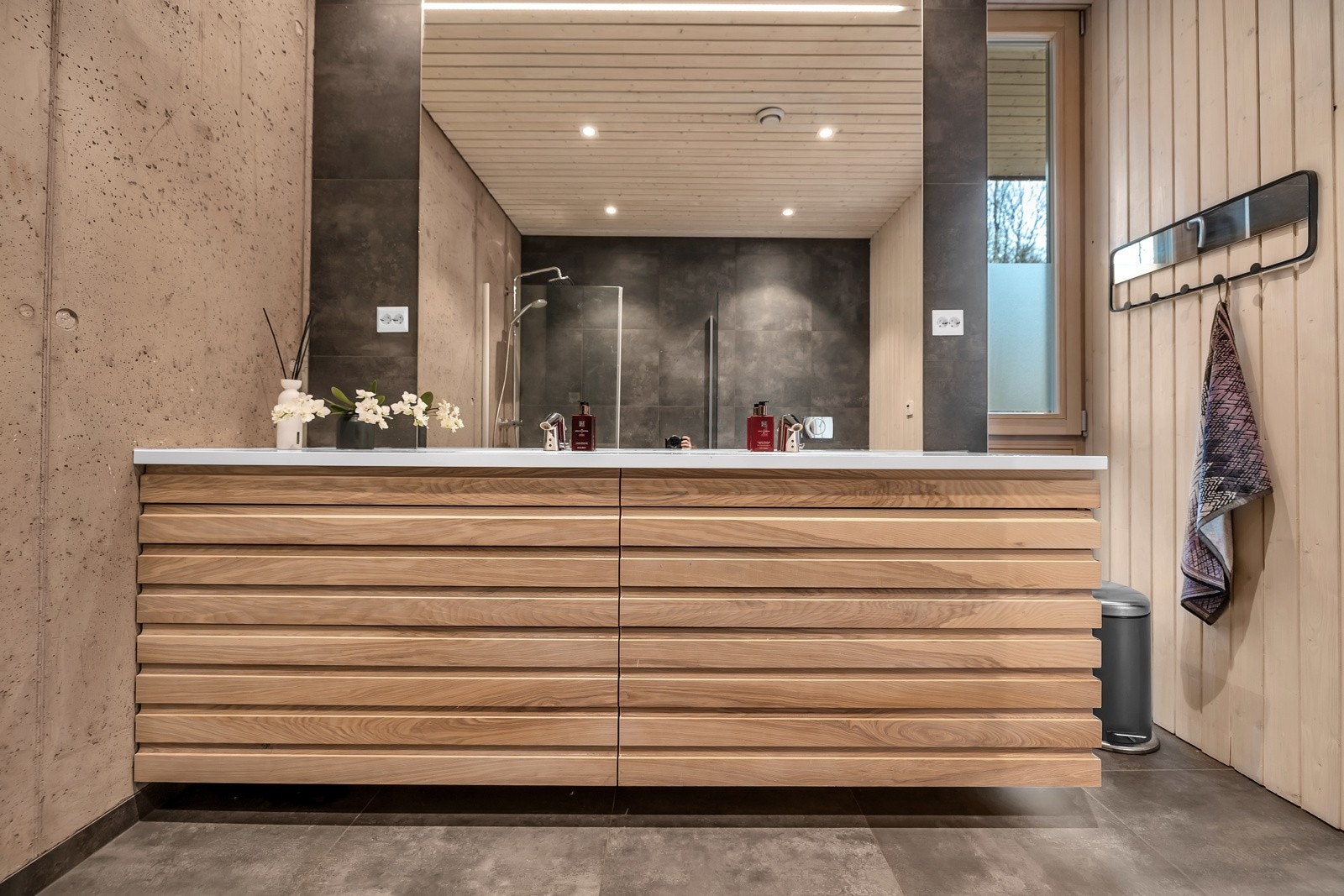 Badet er lekkert en har en flott materialkombinasjon av tre, betong og fliser Galleribilde