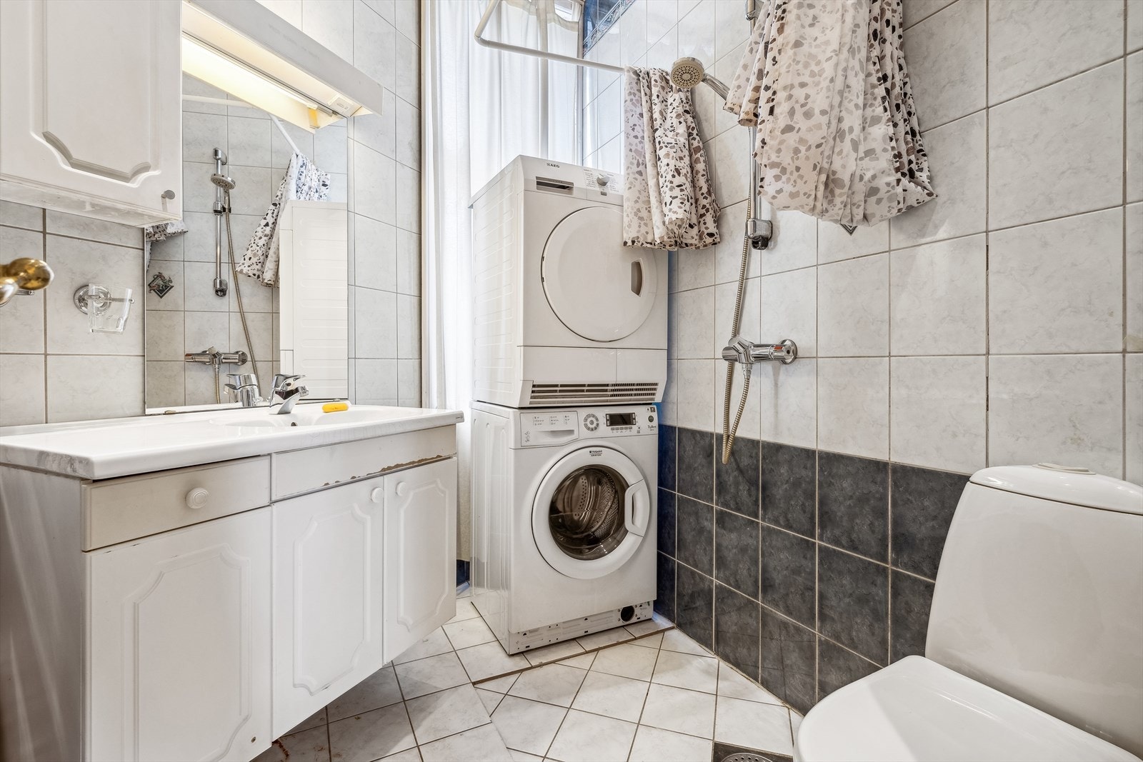 Badet er innredet med servantskap, vegghengt speil, toalett og opplegg for vaskemaskin. Galleribilde