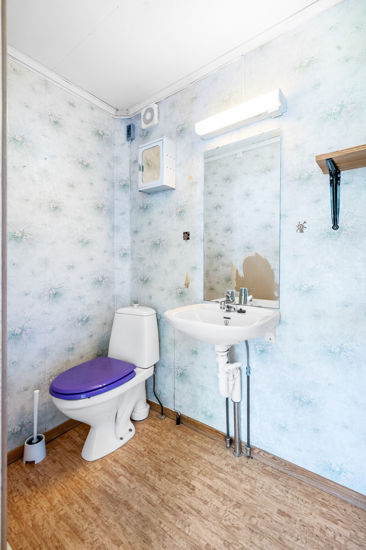 Toalettrom innenfor soverommet. På gulvet er det belegg, veggene har blå mønstrete tapet og himlingen er med hvitmalt slett flate. Galleribilde