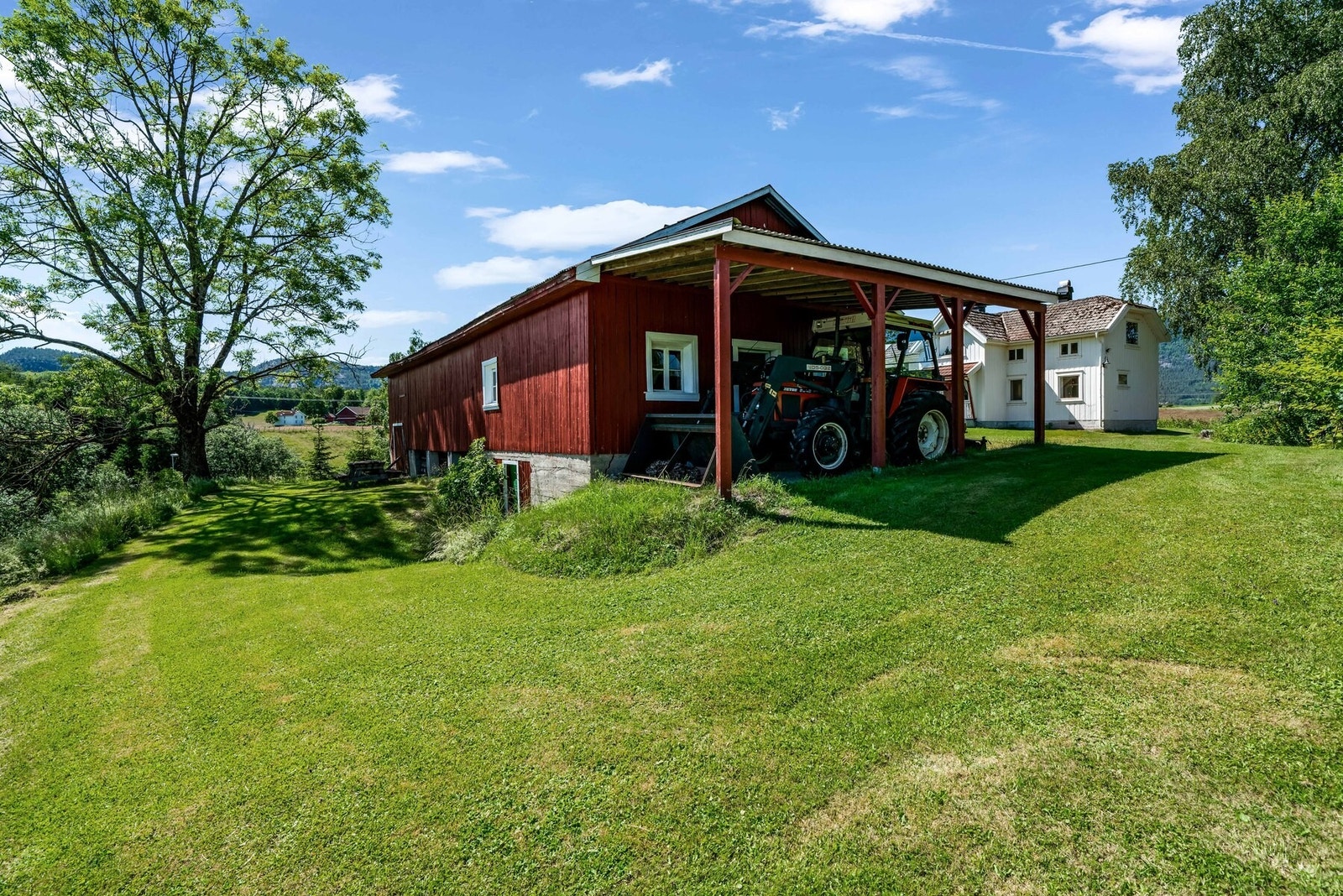 På baksiden av uthuset er det koselig opparbeidet en sitteplass under det store treet. Galleribilde