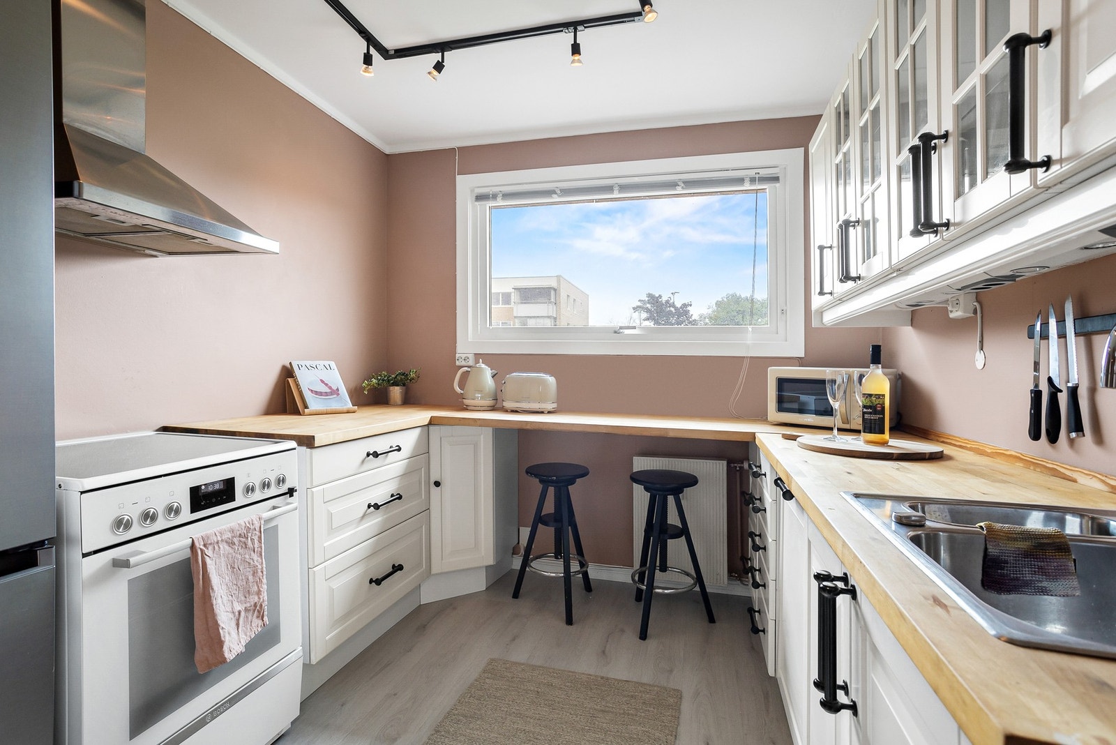 Det hyggelige kjøkkenet har god skap- og benkeplass i innredning langs to vegger, og spiseplass ved fritthengende benkeplate under kjøkkenvinduet. Galleribilde