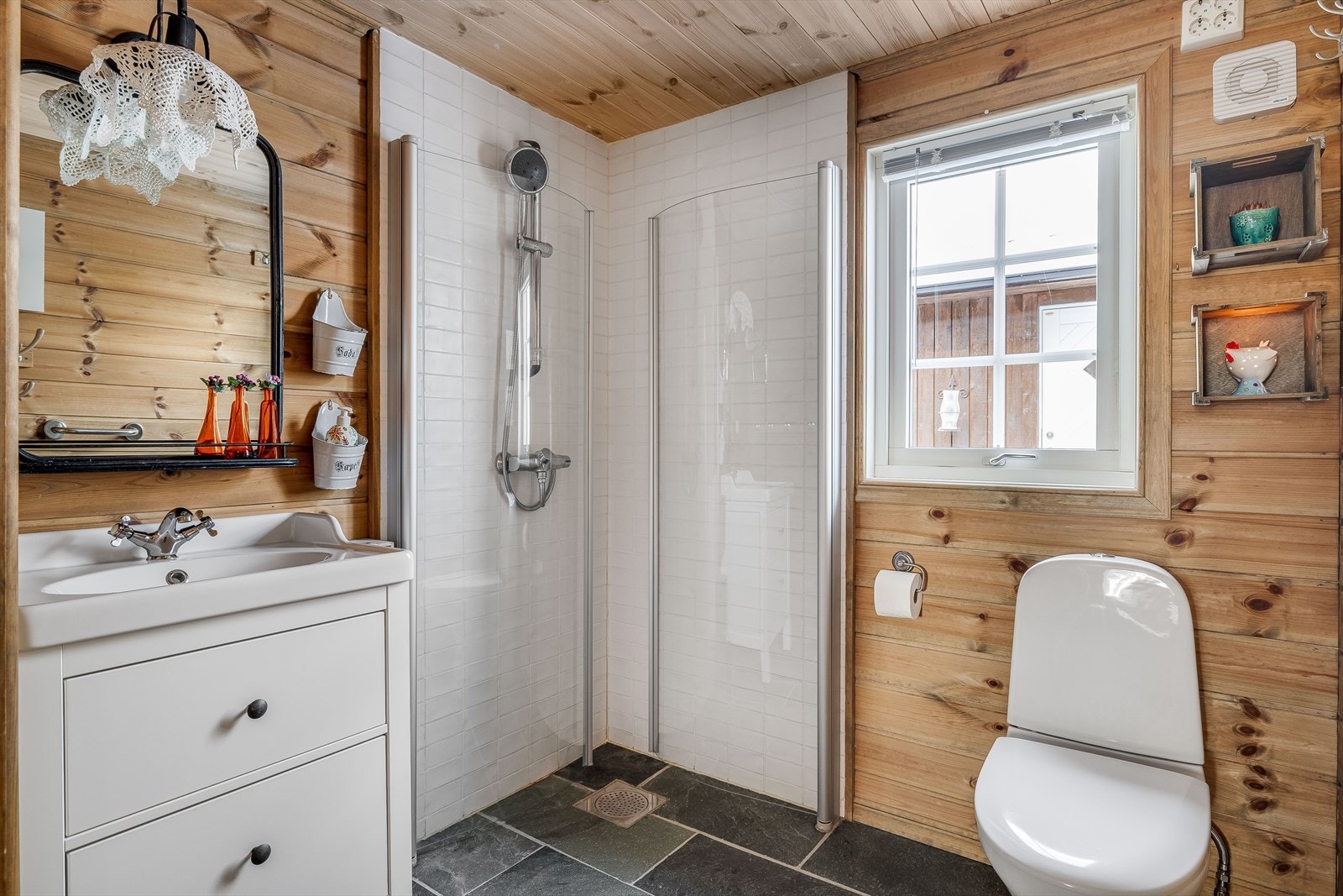 Bad med skyvedør for enkel adkomst. Badet har skiferfliser og varmekabler på gulvet, fliser i dusjen og panel på øvrige overflater. Galleribilde
