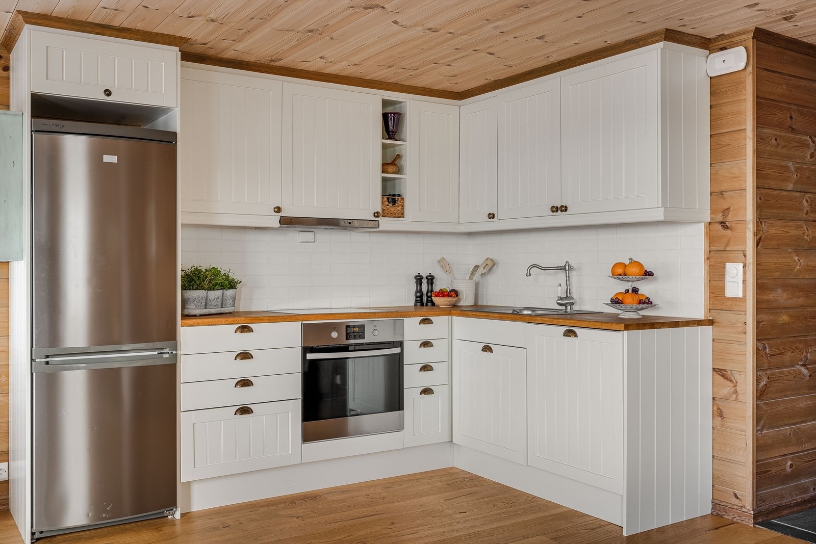 Innredningen er lys og tidløs med laminerte skrog og profilerte fronter. Heltre benkeplate med oppvaskkum i rustfritt stål. Det er fliser i benkeryggen. Galleribilde