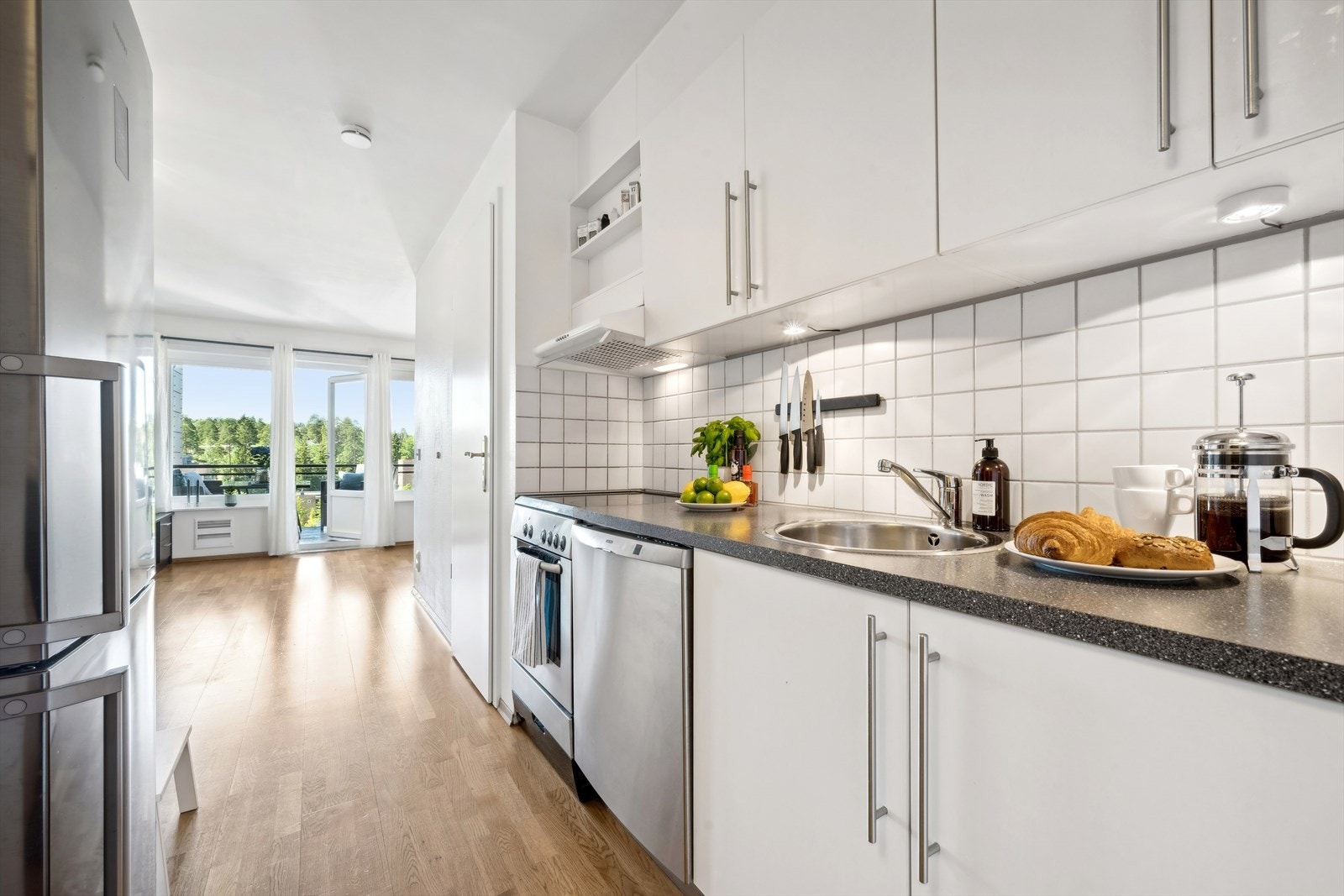 Kjøkkenet har innredning med slette fronter og benkeplaten er av laminat og fliser på vegg over benk. Galleribilde