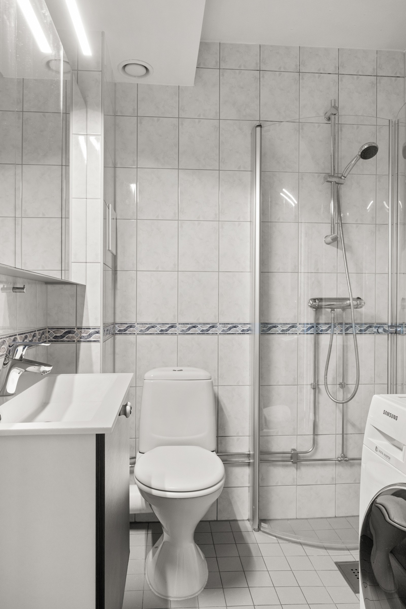 Delikat, flislagt bad med opplegg for vaskemaskin. Galleribilde