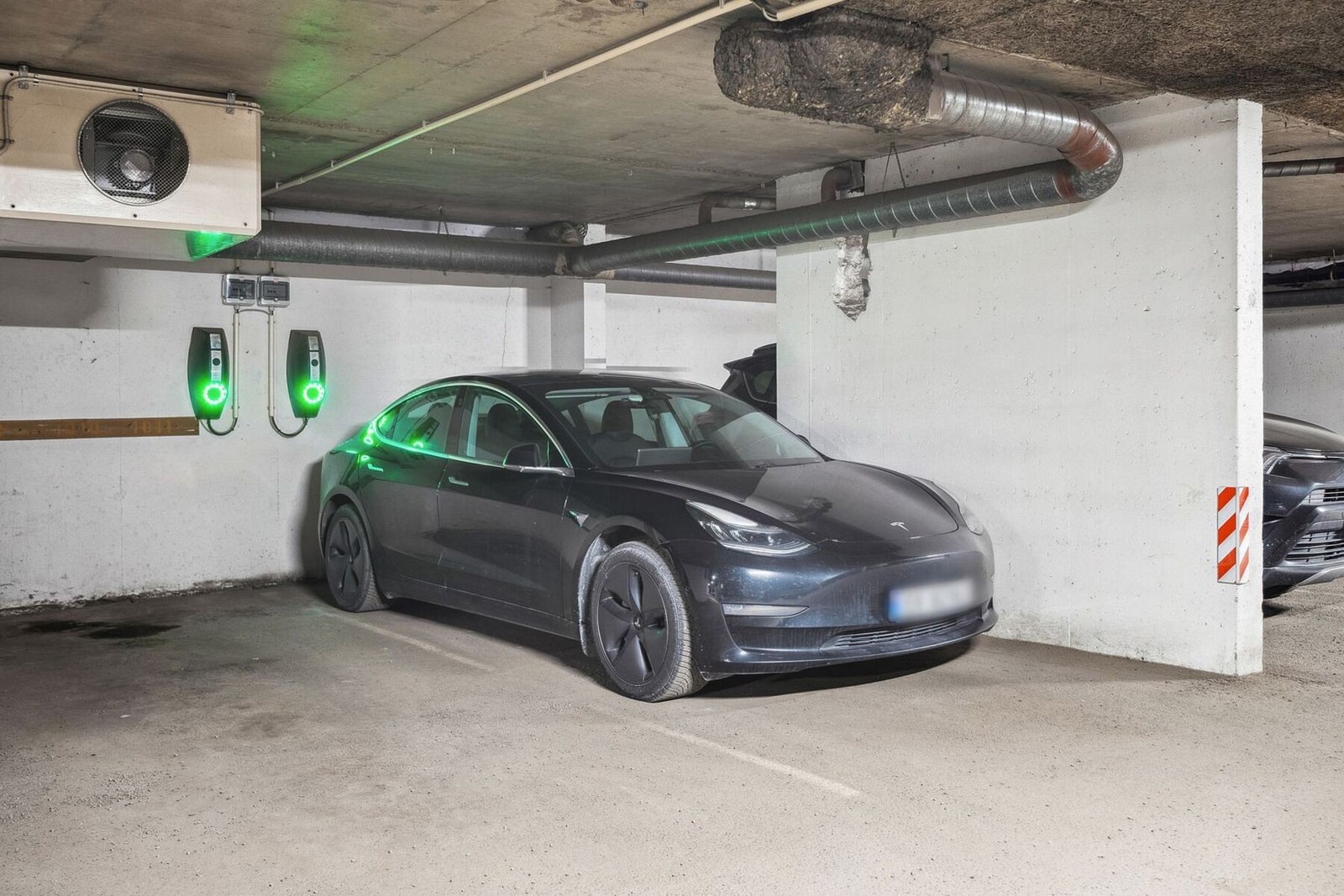 Parkeringsplass i felles underjordisk garasje, med El-bil lader Galleribilde