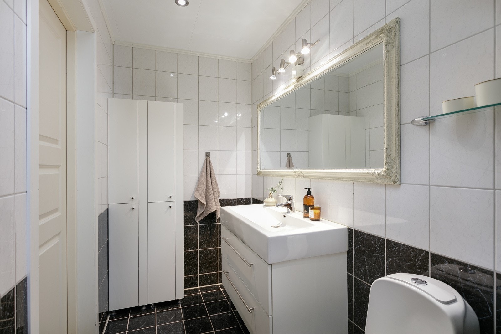 Badet har flislagte overflater, varmekabler, servantinnredning med 2 skuffer og innholdsrikt høyskap. Galleribilde