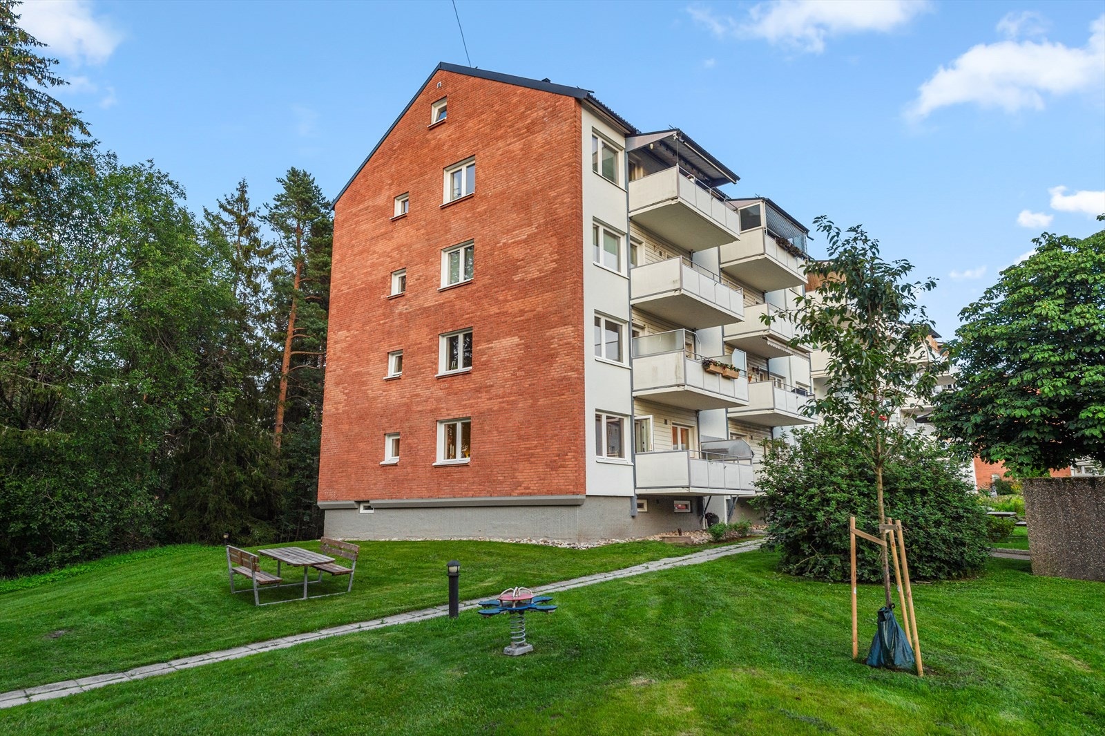 Pent opparbeidet uteområde med steinbelagte internveier, gressplen og sittebenker Galleribilde