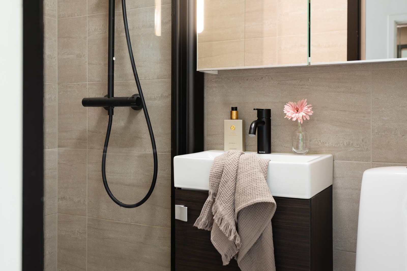 Badet er utstyrt med dusjhjørne i glass, servantinnredning og gulvstående toalett. Galleribilde