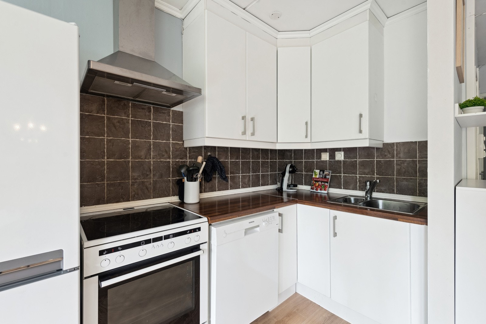 Benkeskapsbelysning og stikkontakter under overskap. Frittstående hvitevarer. Kjøleskap med frysedel, oppvaskmaskin og komfyr. Galleribilde