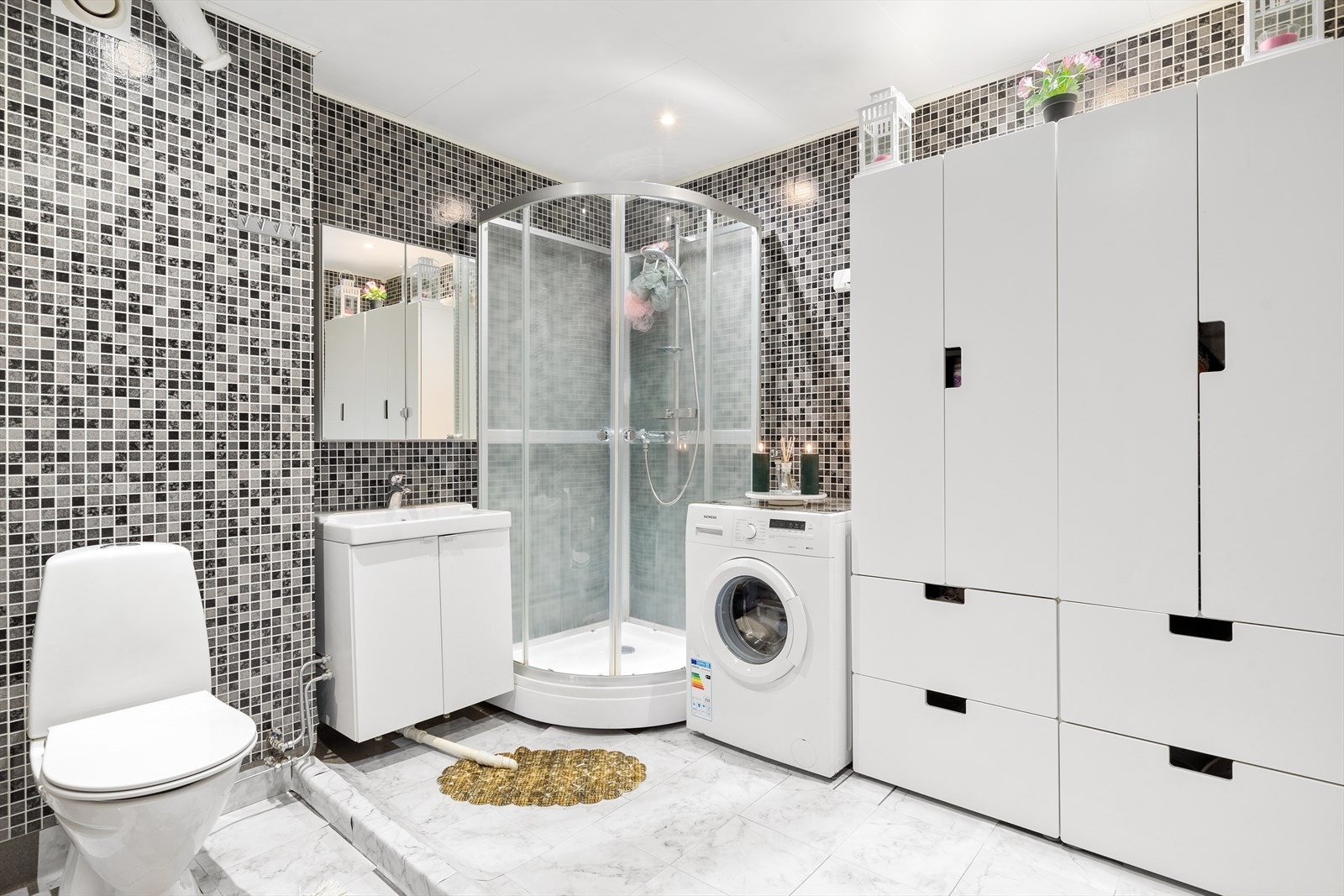 Pent bad med innredning bestående av klosett, dusjkabinett og baderomsinnredning med speil. Opplegg for vaskemaskin Galleribilde