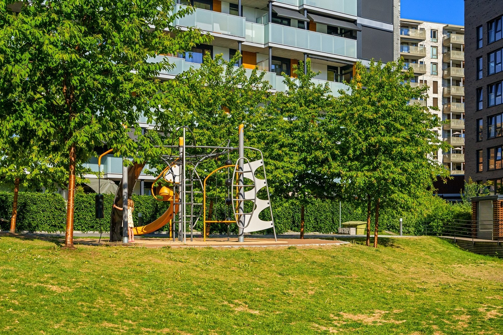 Flotte fellesareal med lekeapparat, sittegrupper og beplanting. Galleribilde