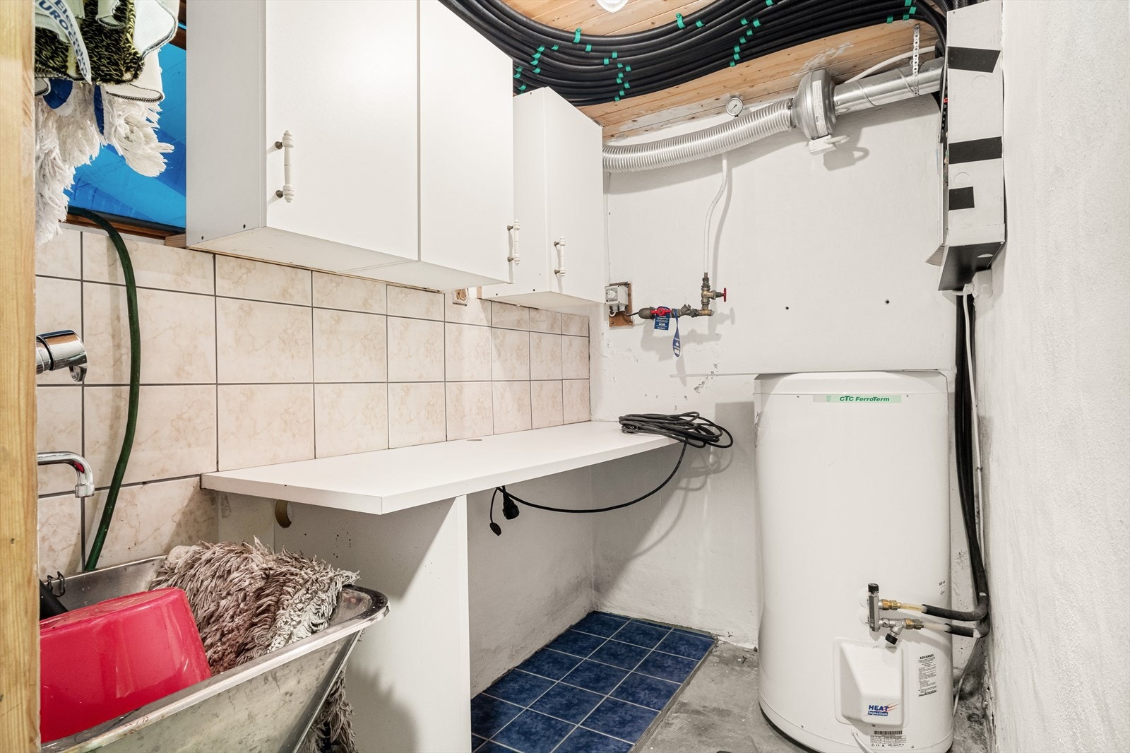 Vaskerommet inneholder utslagsvask, benkeplate, varmtvannstank og opplegg for vaskemaskin Galleribilde