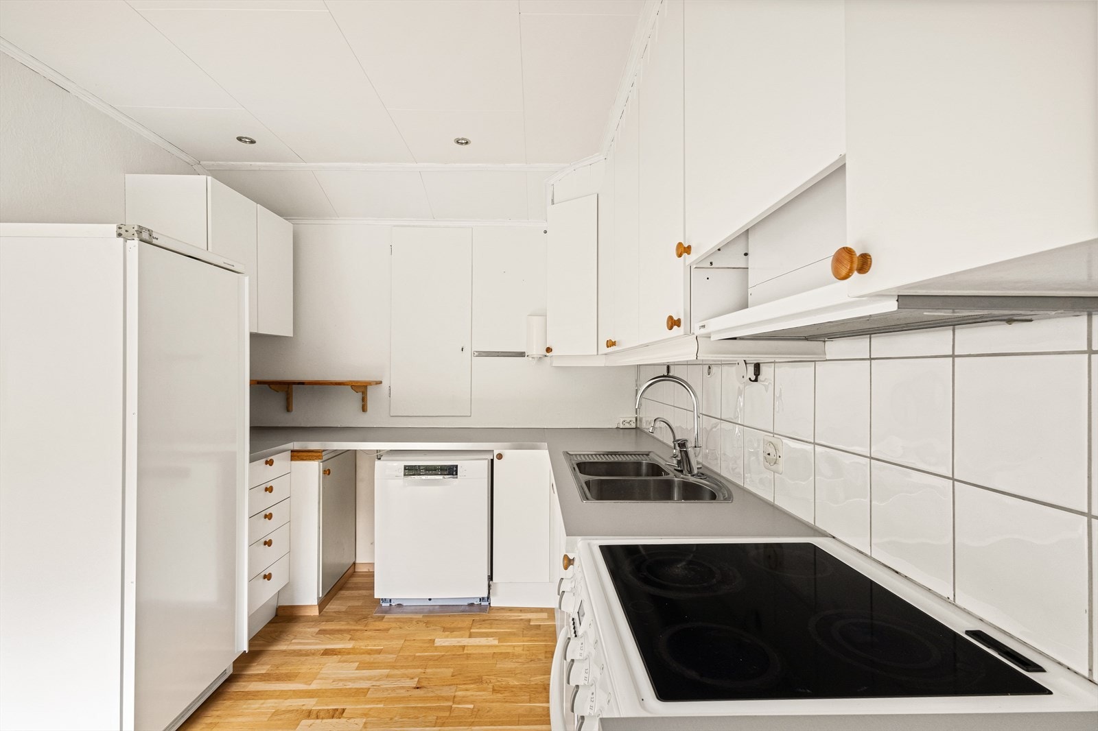 IKEA kjøkken, innredet med slette hvite fronter og laminat benkeplate. Opplegg for vaskemaskin Galleribilde