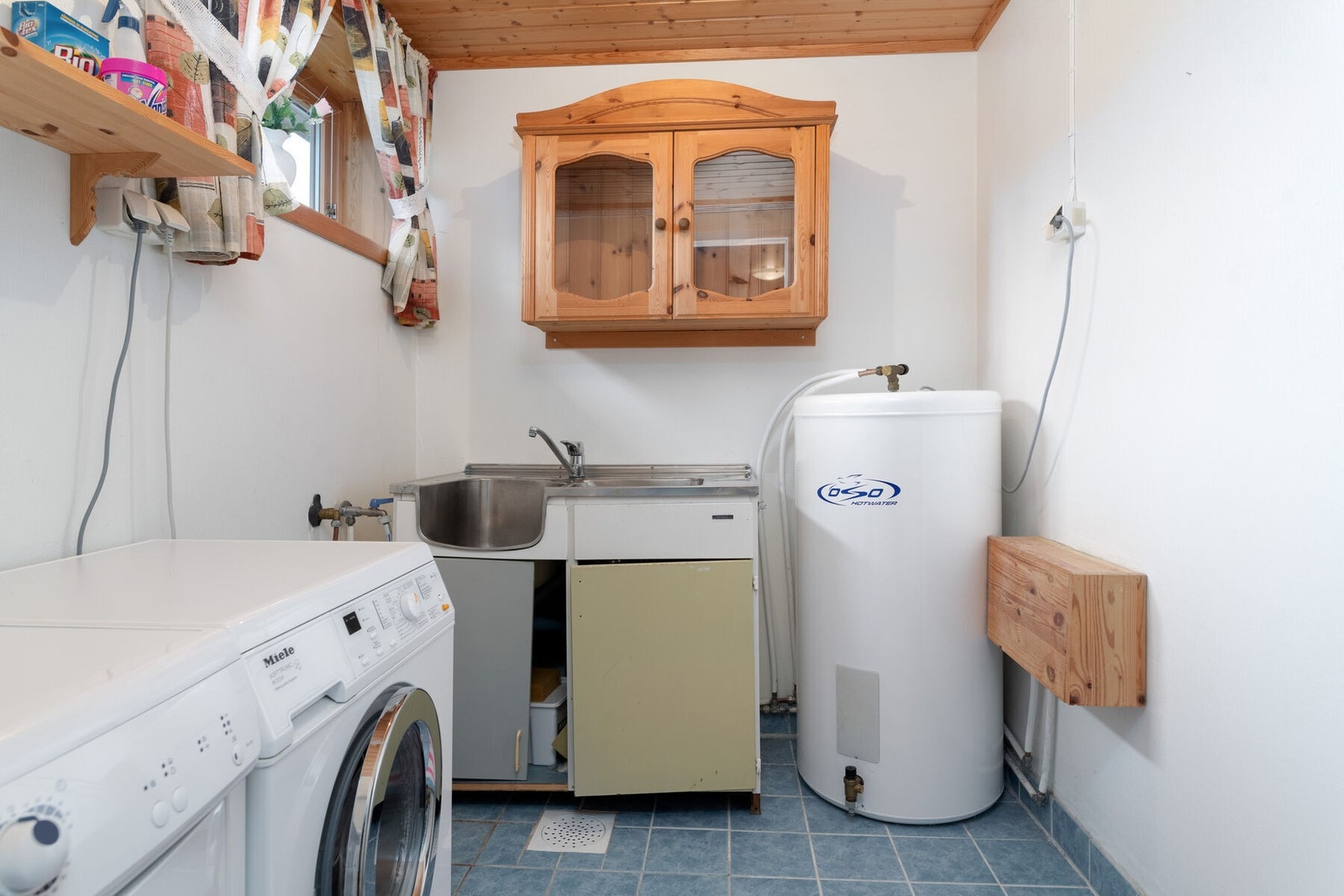 Vaskerommet har opplegg for vaskemaskin og innredning med nedfelt skyllekar i stål Galleribilde