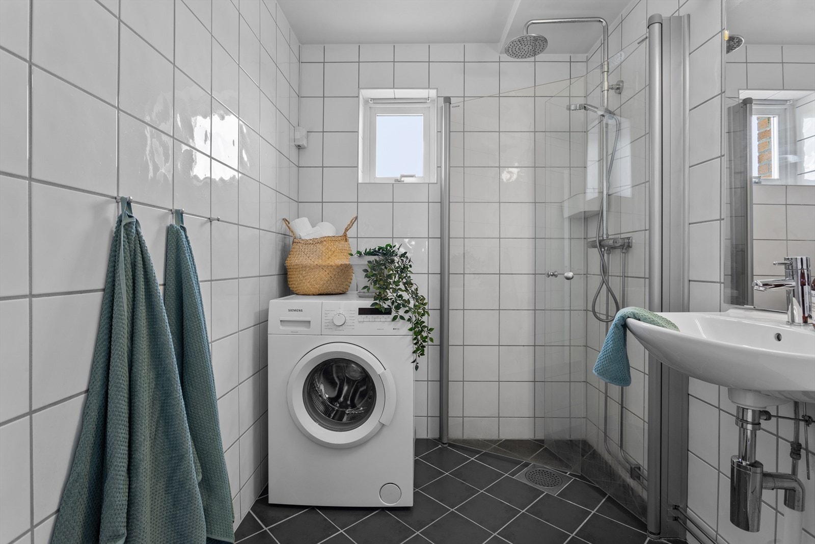 Pent og tidløst baderom med opplegg for både vaskemaskin og tørketrommel. Galleribilde