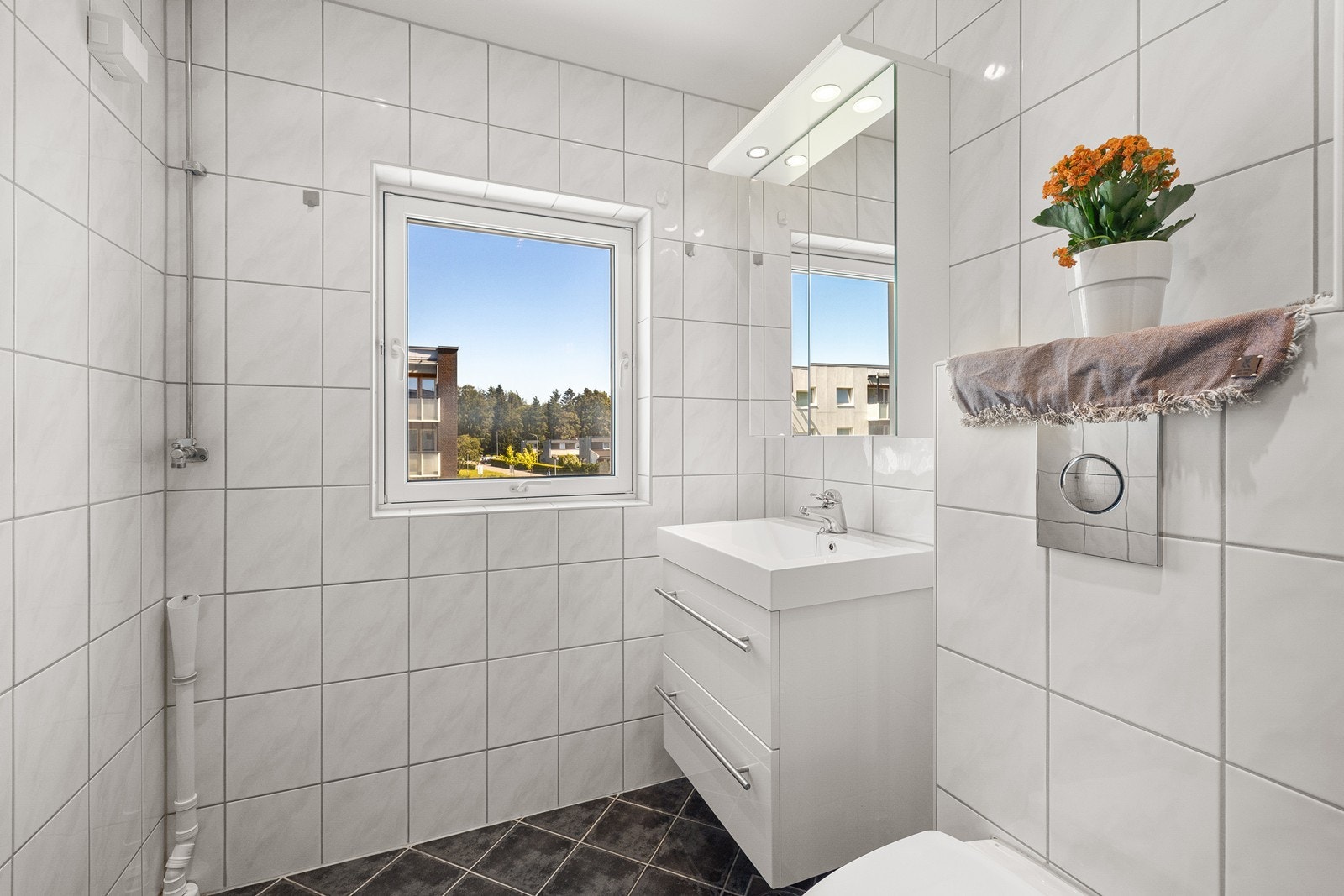 Badet er innredet med servant i baderomsinnredning, opplegg for vaskemaskin, vegghengt toalett og dusjhjørne. Galleribilde