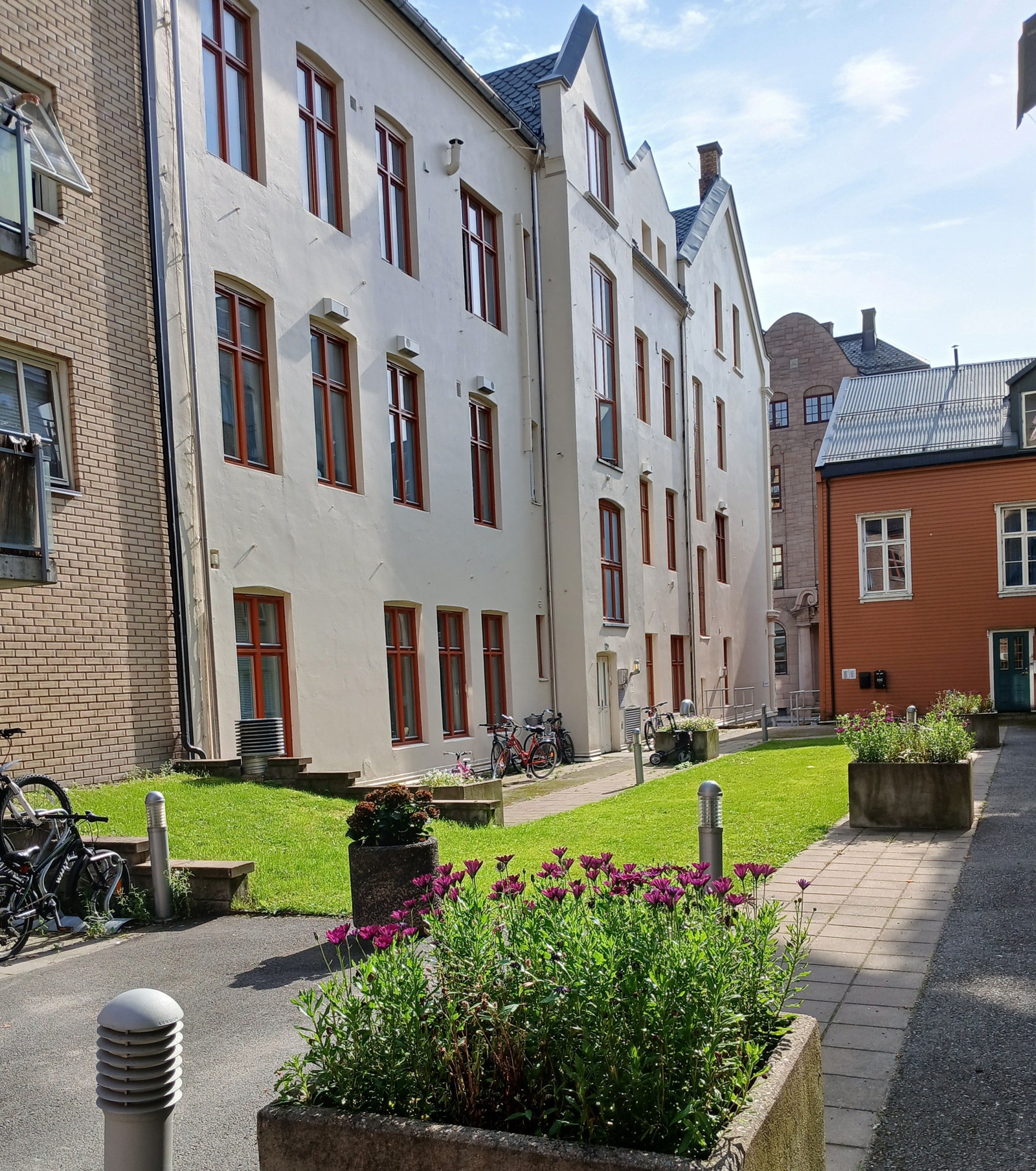 Ryddig og beplantet bakgård med sykkelstativ. Sykkelbod i første etasje. Galleribilde