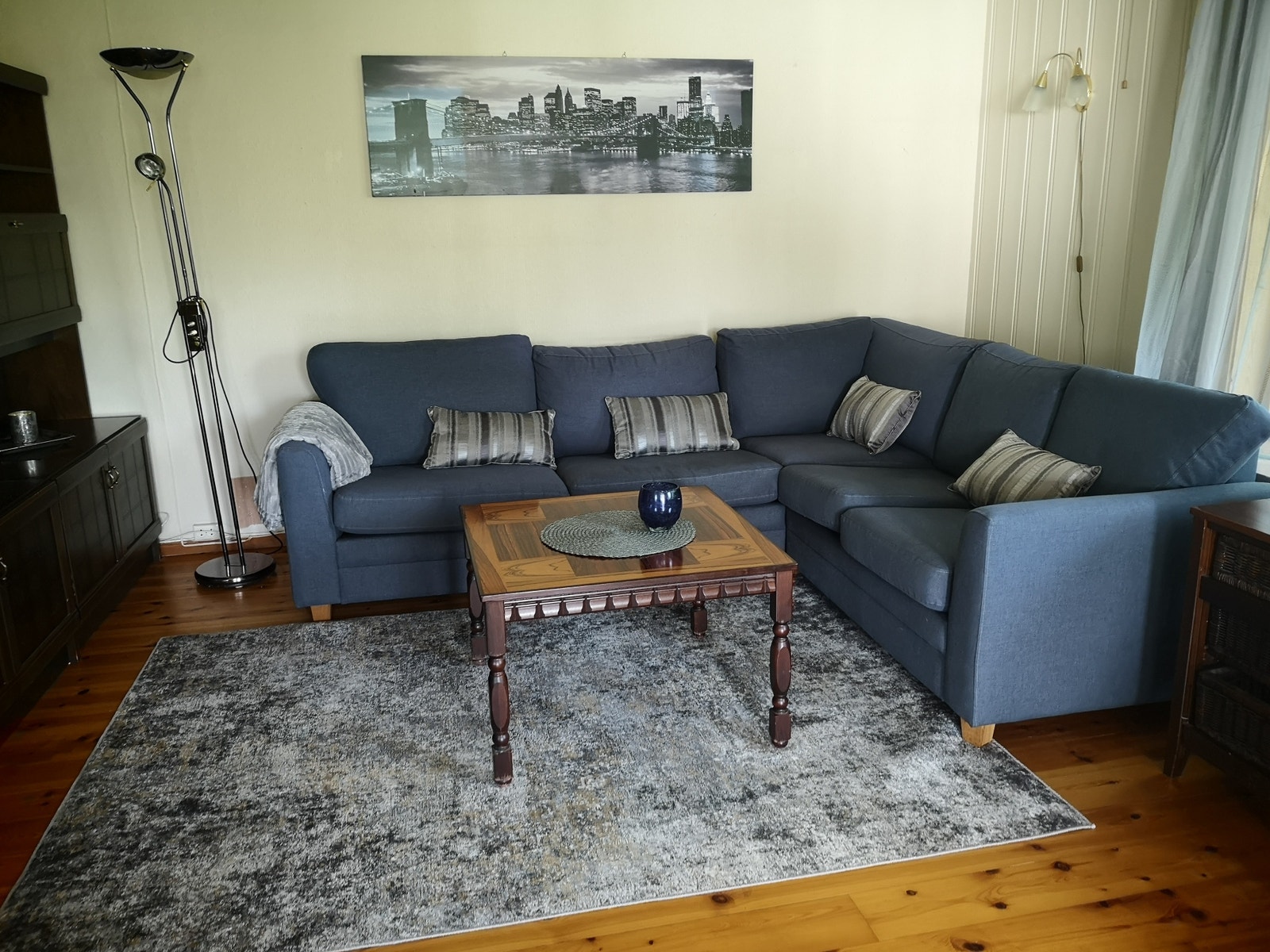 Romslig stue med stor sofa, store vinduer med utsikt ut mot skog. Usjenert Galleribilde