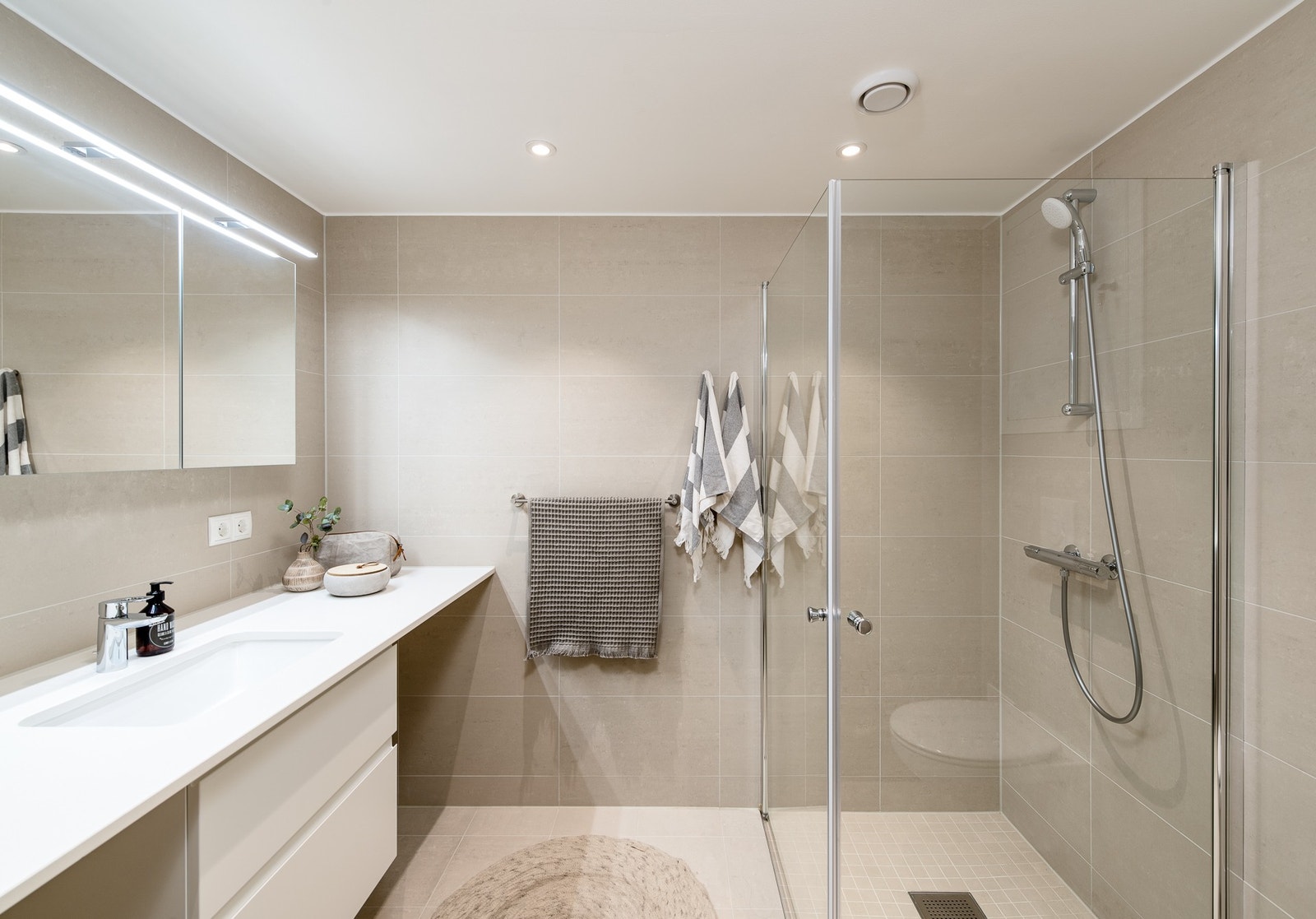 Lyst og innbydende bad med gulvvarme. Det er opplegg for vaskemaskin og tørketrommel på badet. Galleribilde