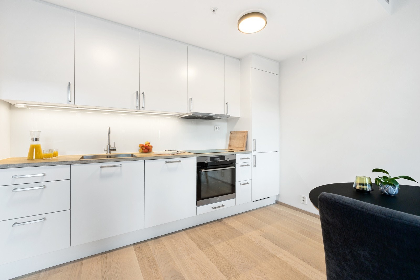 Hvit kjøkkeninnredning med slette fronter og integrerte hvitevarer. Galleribilde