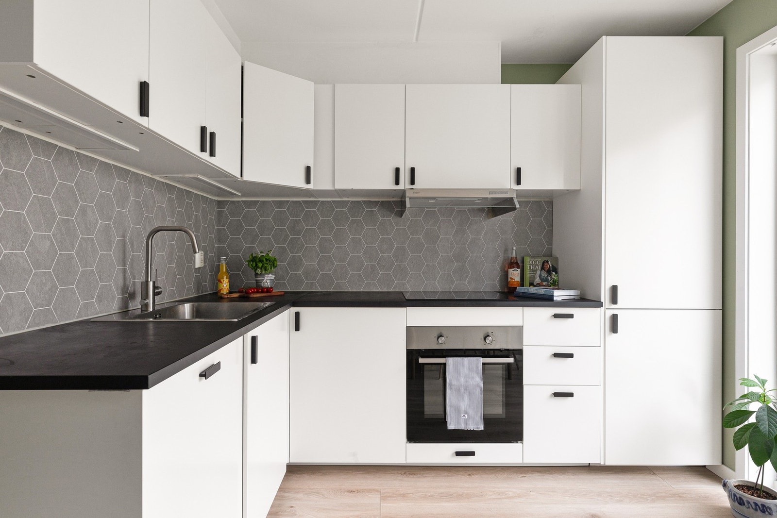 Kjøkkeninnredningen fra 2021 har stilrene, glatte fronter og moderne belysning under overskapene, som skaper en lys og innbydende atmosfære. Galleribilde