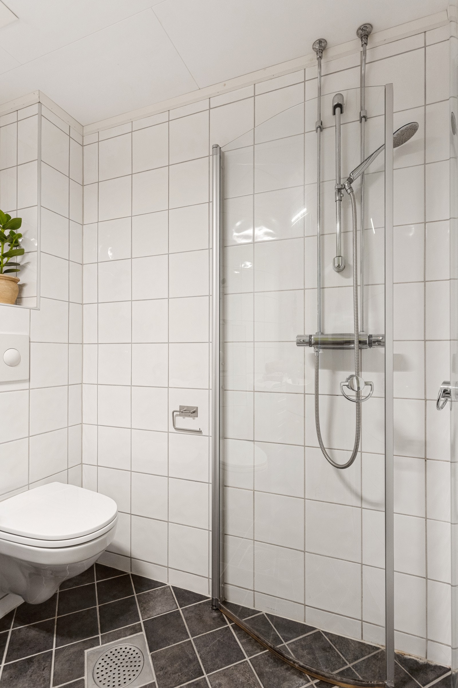 Pent bad med veggmontert klosett og dusj med ut/- og innfellbar svingdør. Galleribilde