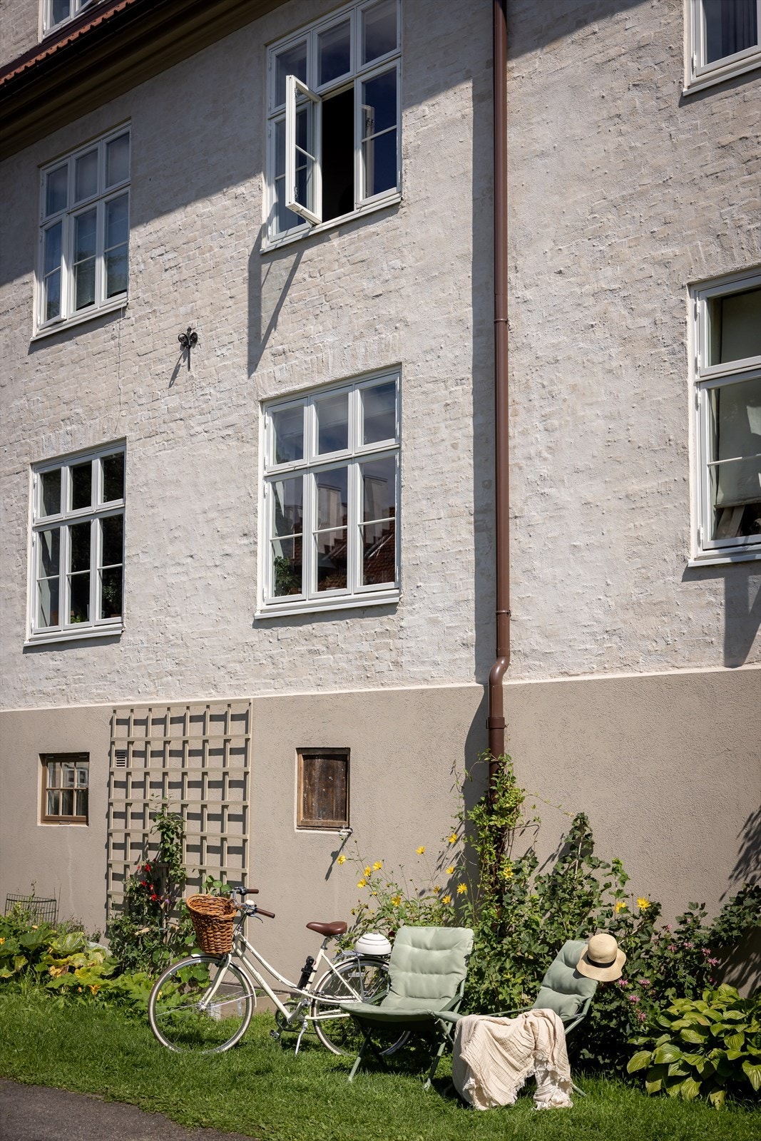 Rett utenfor leiligheten (åpent vindu) er det en pent opparbeidet og velholdt bakgård med store plenarealer, blomsterbed og prydbusker Galleribilde