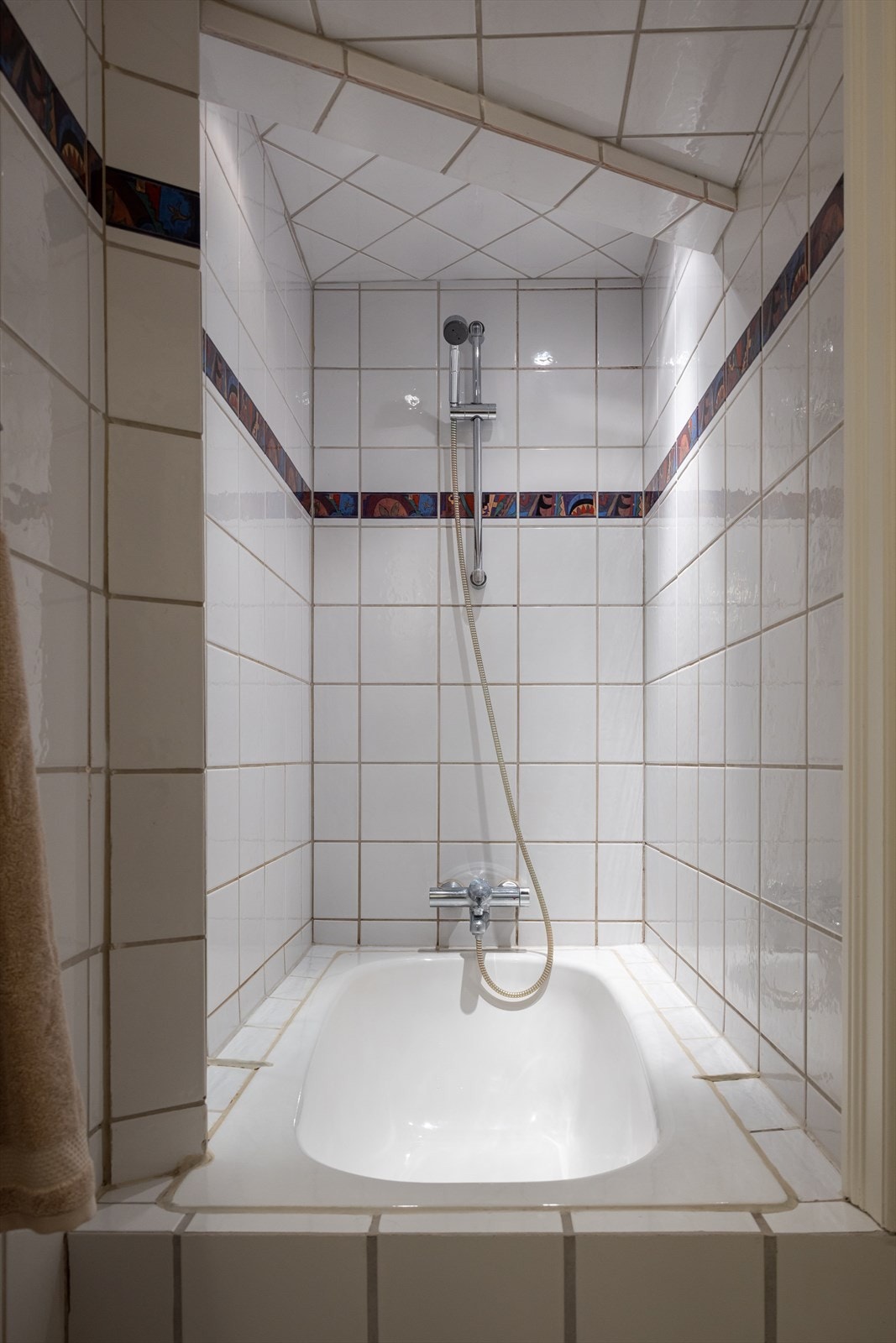 Badet er innredet med toalett, baderomsinnredning og innmurt badekar Galleribilde