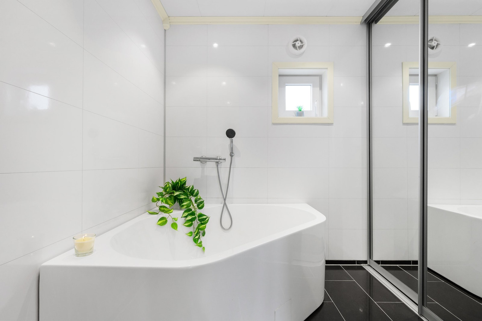 Pent hjørnebadekar. Skyvedører med speildører skjuler vaskemaskin og tørketrommel. Galleribilde
