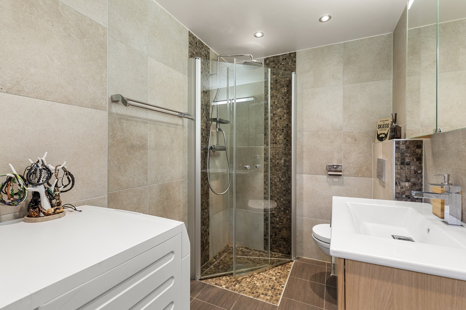 Badet er fra 2015 og har innredning med nedfelt servant, veggmontert toalett og dusjvegger/hjørne. Galleribilde