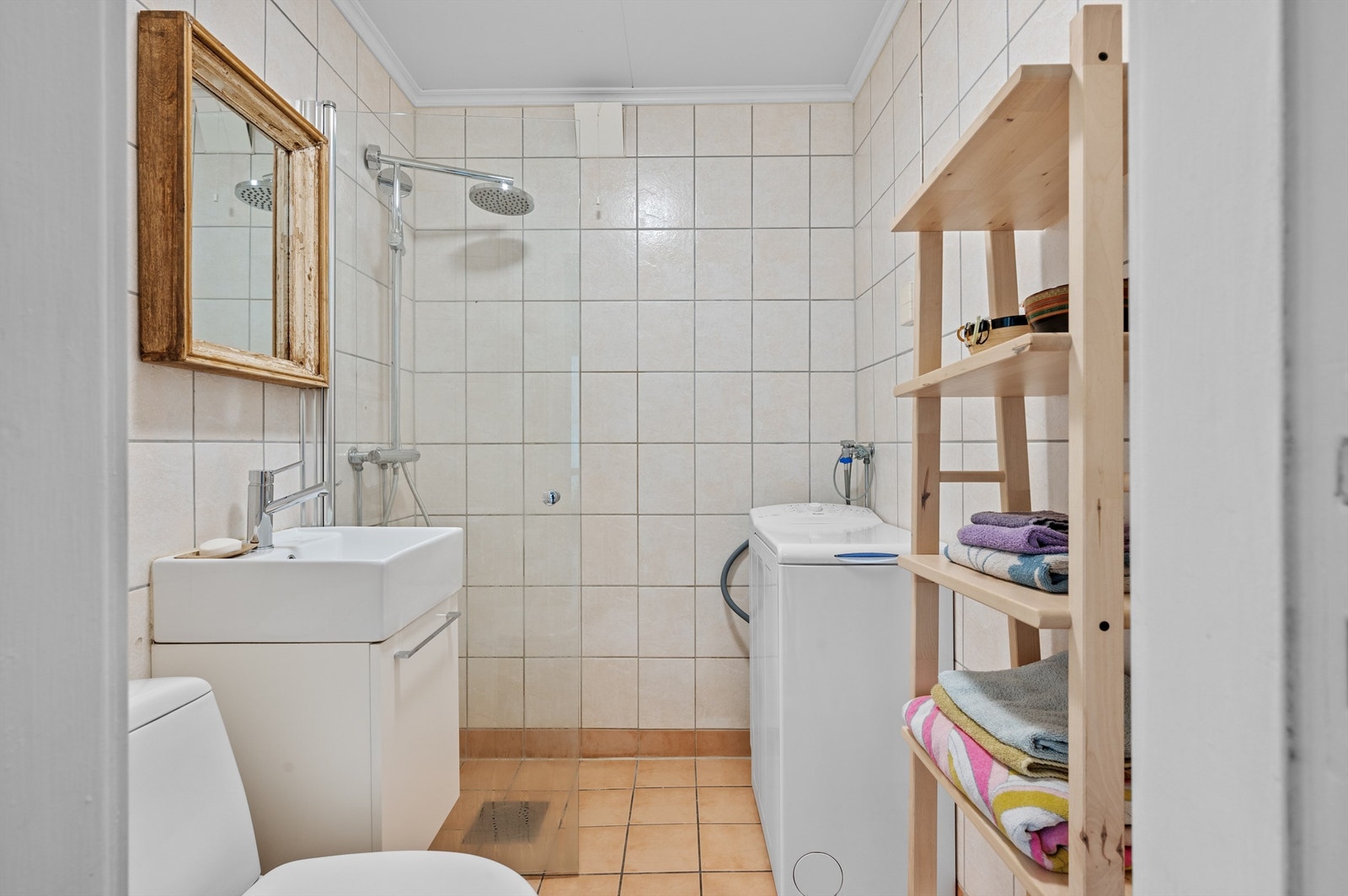 Badet er pent flislagt på gulv og vegger med varme i gulvet. Baderomsinnredningen består blant annet av servant med et praktisk og fint speil over servanten. Galleribilde