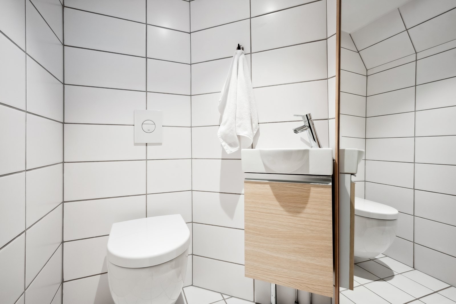 Toalettrom i kjeller er utstyrt med servant og veggfestet toalett med innebygget sisterne. Galleribilde